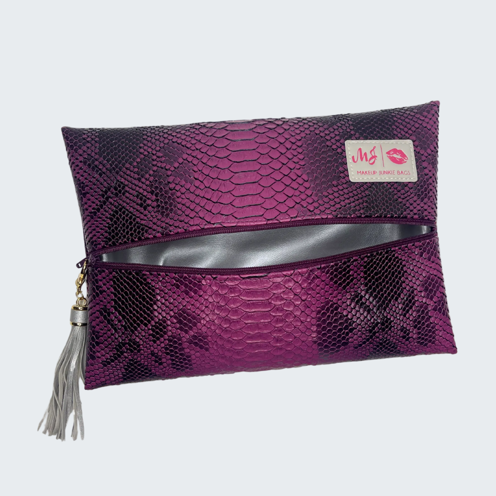 Purple snakeskin patterned pouch with a silver zipper and tassel on a white background