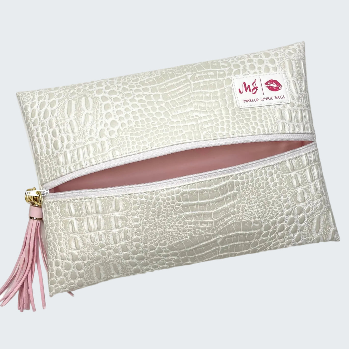 White crocodile-patterned makeup bag with pink interior and tassel on a white background