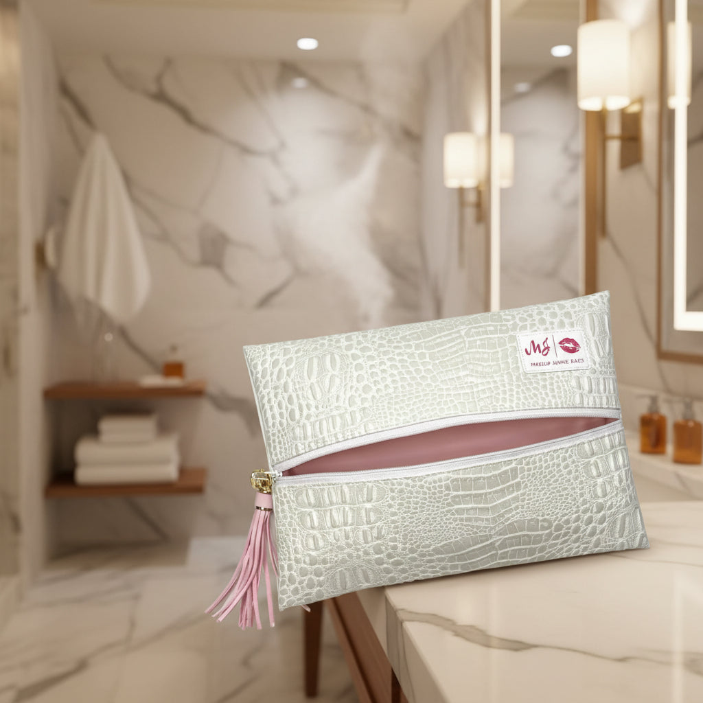 An off-white faux-crocodile leather makeup bag with a pink zipper and a pink tassel, featuring a white brand label that reads 'MJ Makeup Jammer Bag'.
