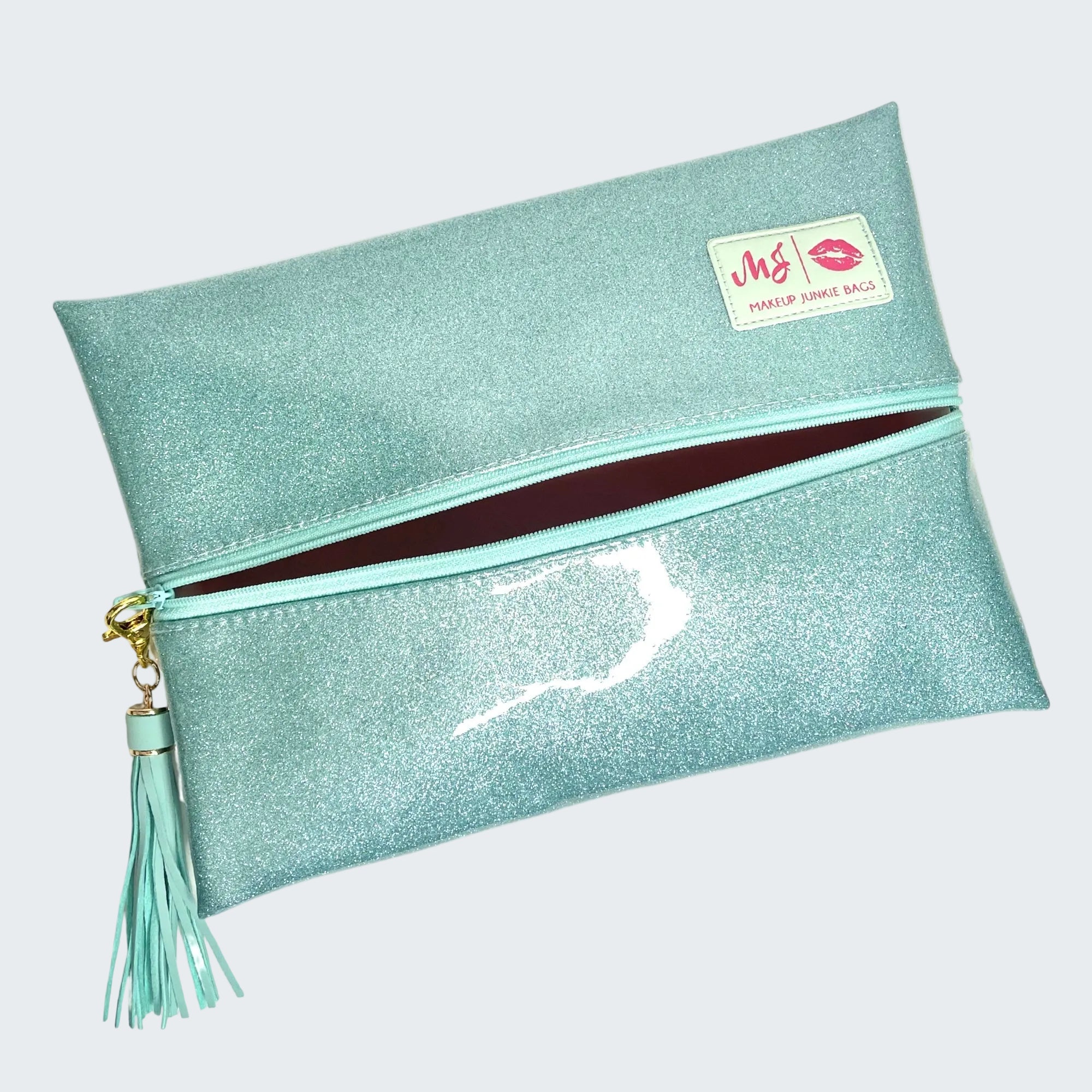 Teal glittery makeup bag with a tassel on a white background