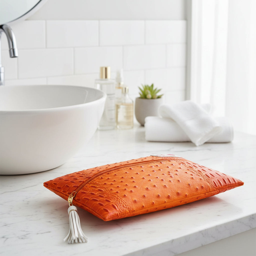 Orange textured clutch bag with a tassel on a white background