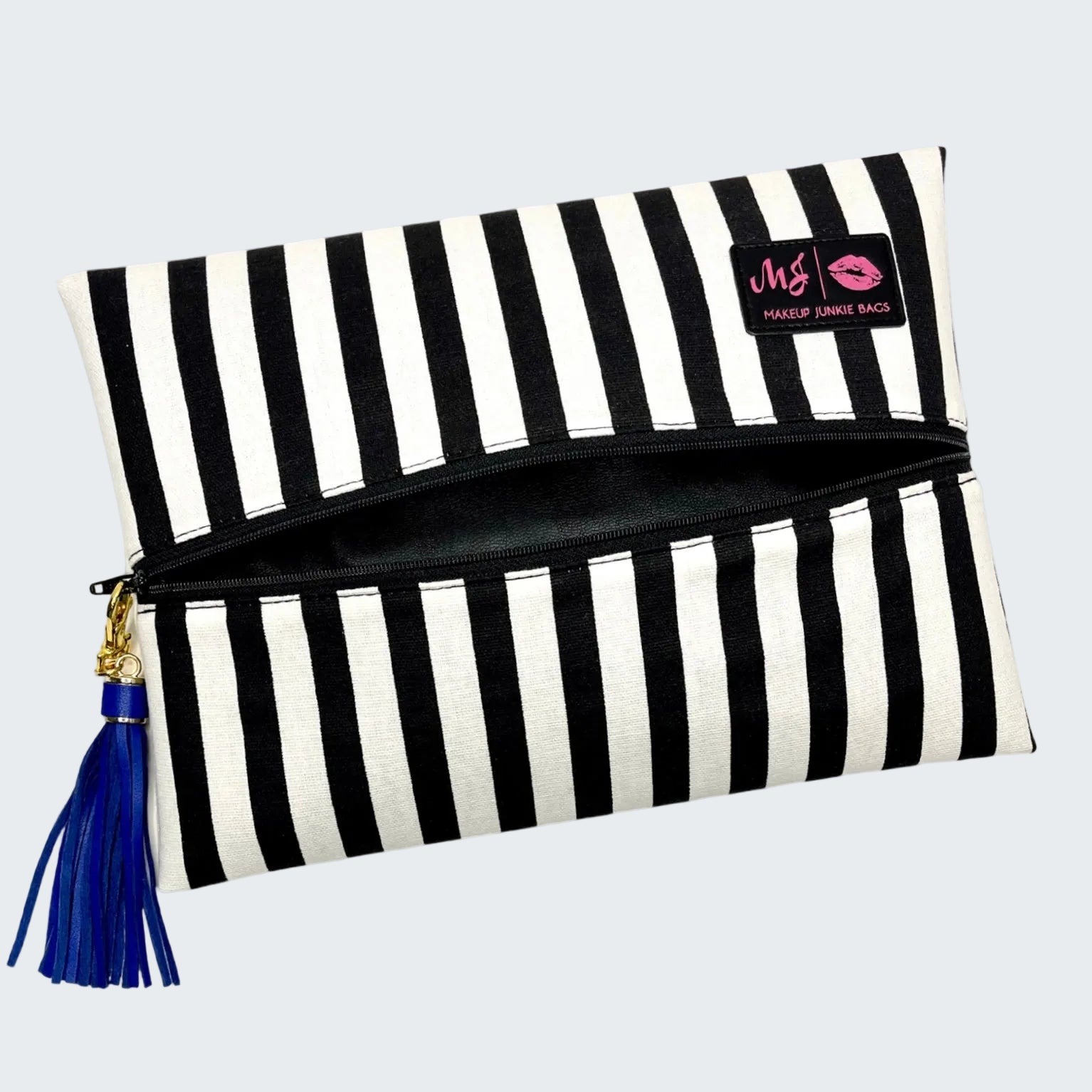 Black and white striped makeup bag with a blue tassel on a white background