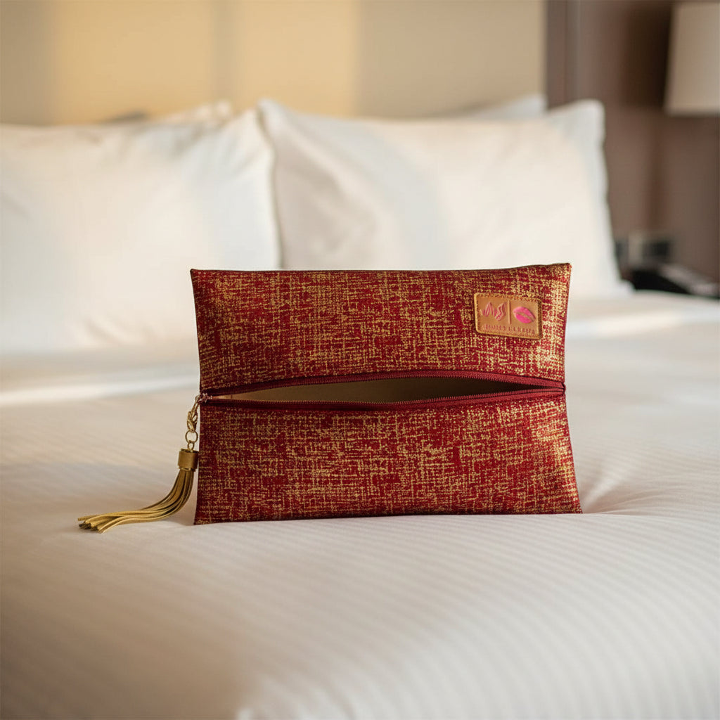 Red and gold patterned clutch bag with a tassel on a white background