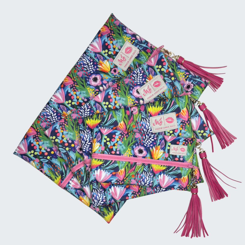 Colorful floral patterned clutch bag with pink tassels on a white background
