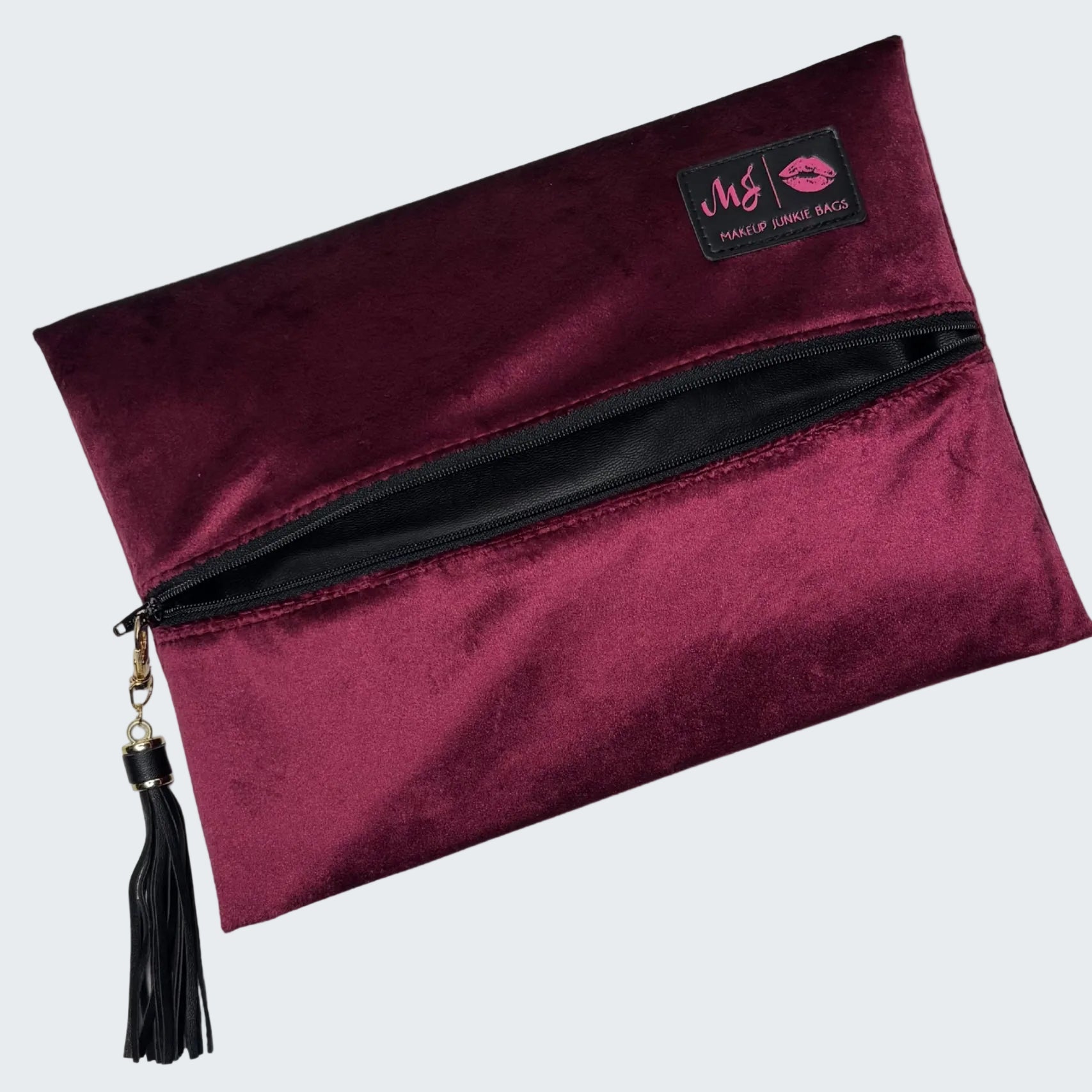 Maroon makeup bag with a tassel on a white background