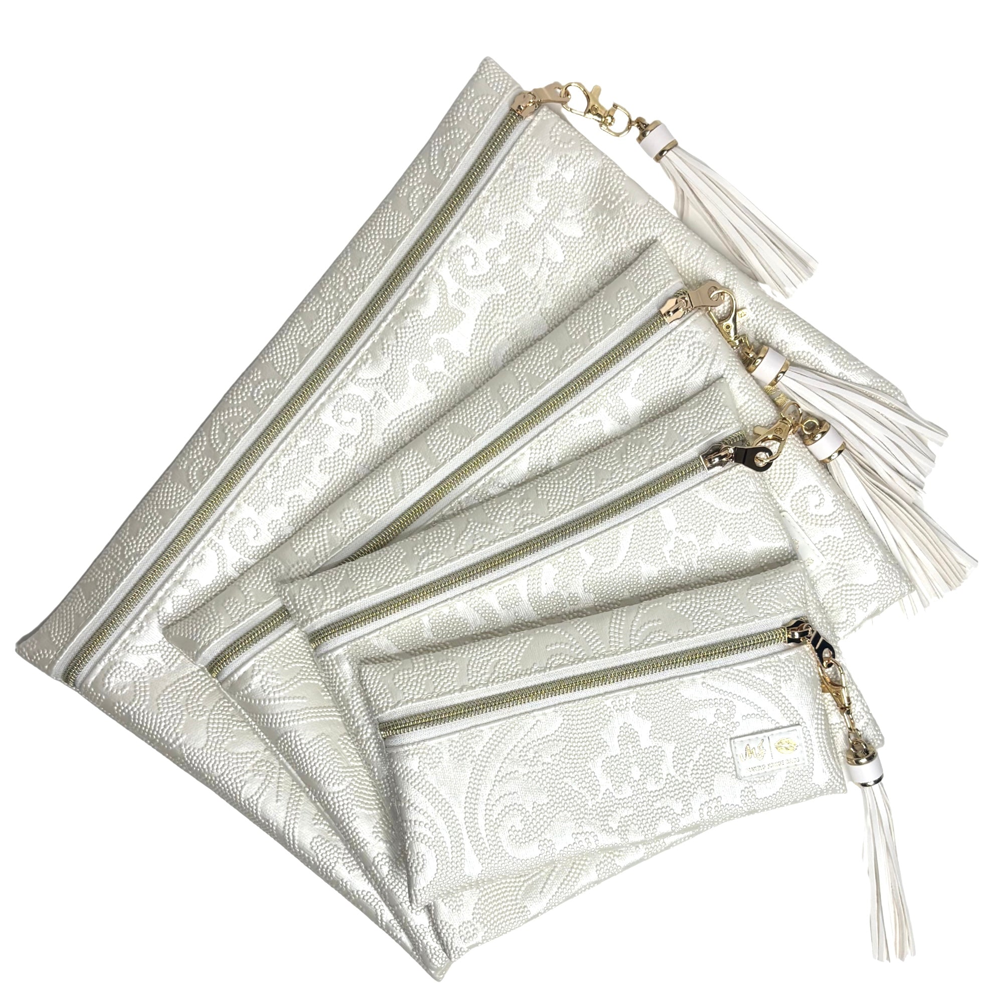 Set of silver patterned pouches with gold zippers and tassels on a white background
