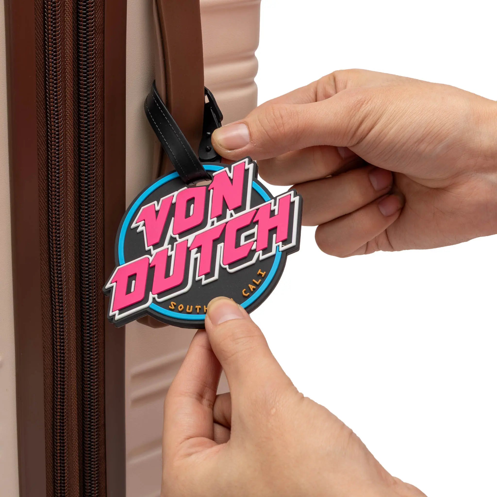 Person attaching a Von Dutch luggage tag to a suitcase