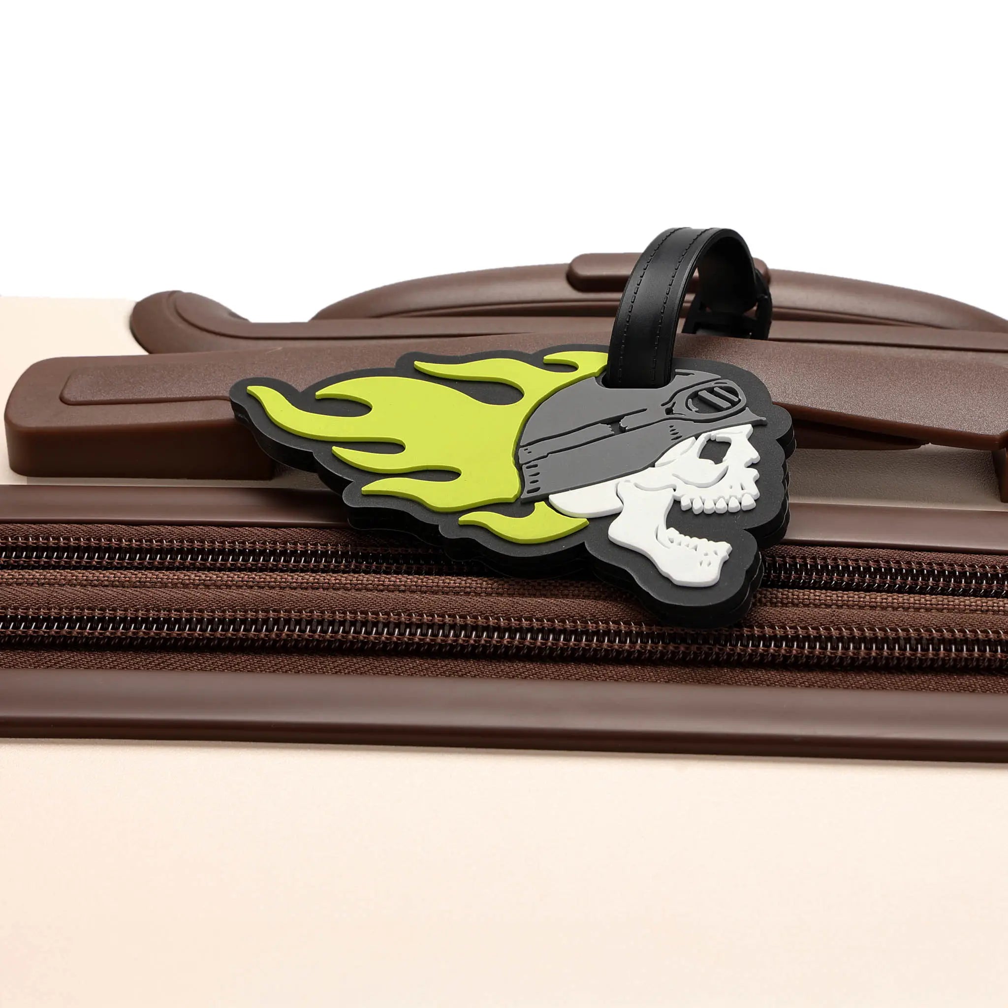 Skateboard-shaped luggage tag with skull design on a brown suitcase.