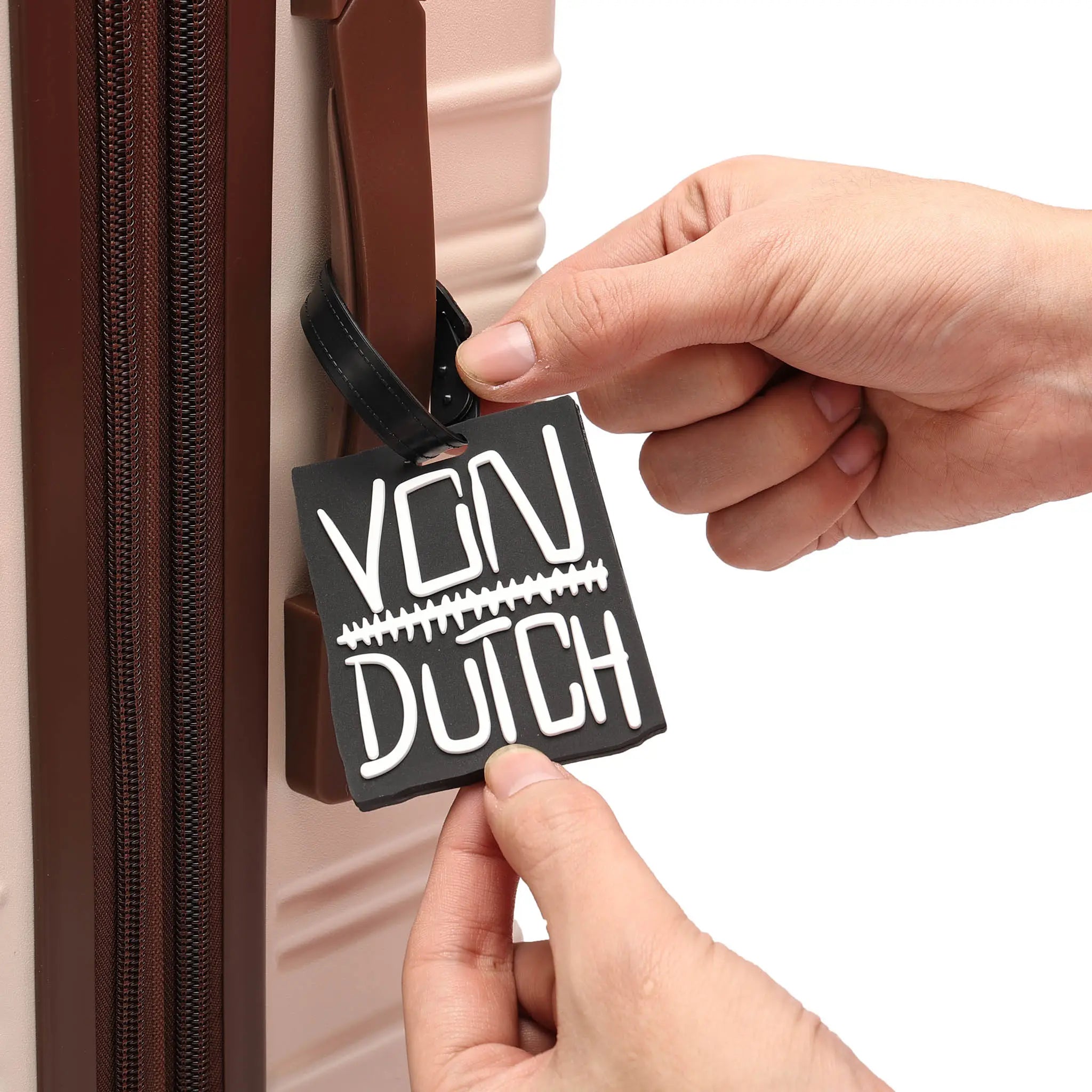 Person attaching a 'Von Dutch' luggage tag to a suitcase.