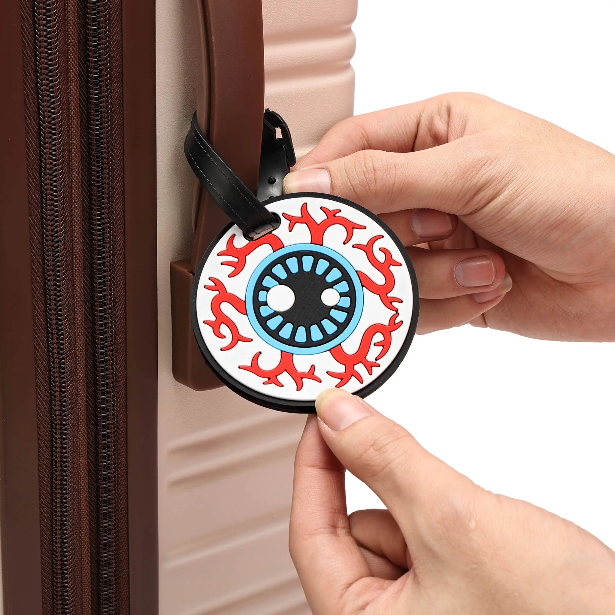 Person attaching a decorative luggage tag with tribal design to a suitcase.
