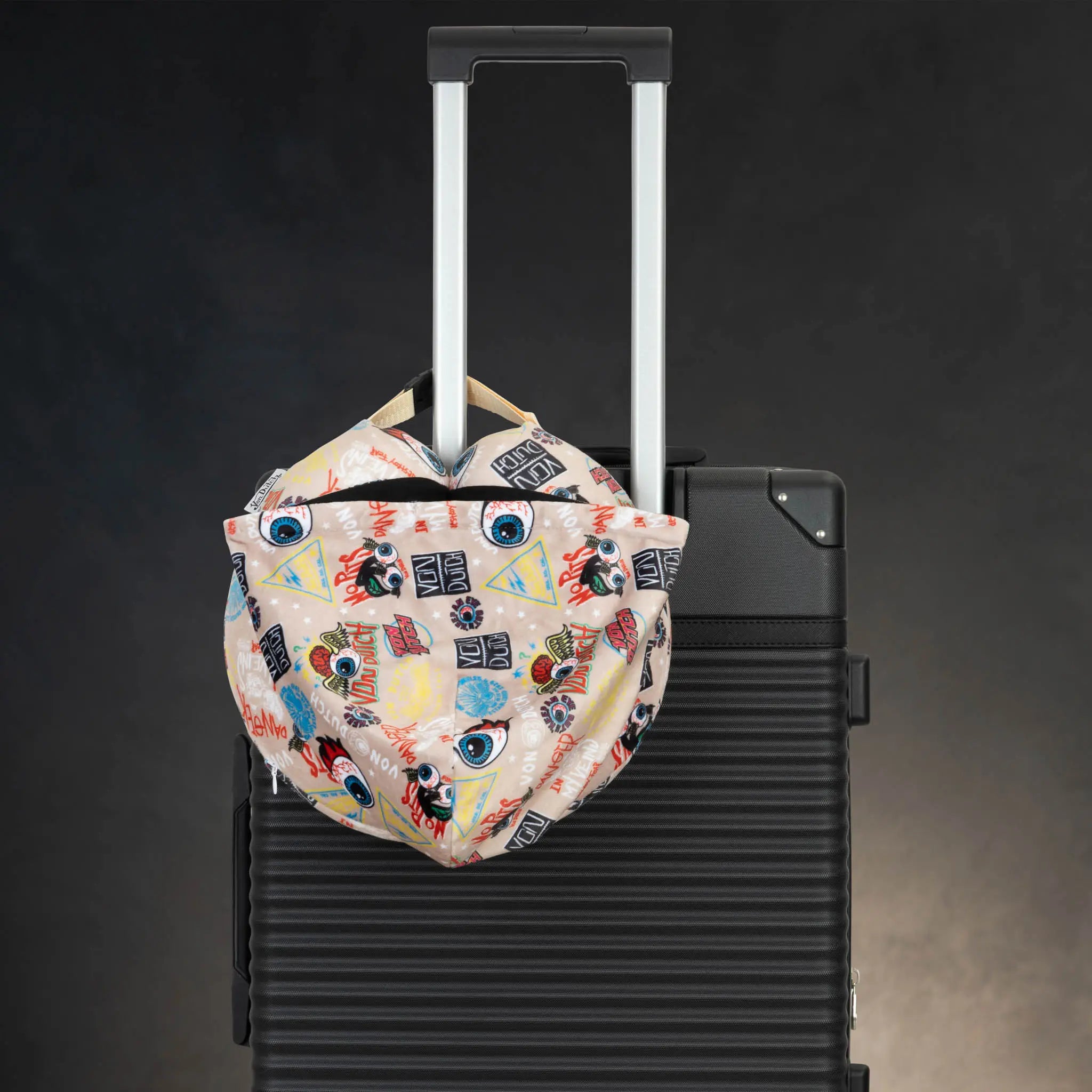 Patterned bag with cartoon character design on a black suitcase against a dark background