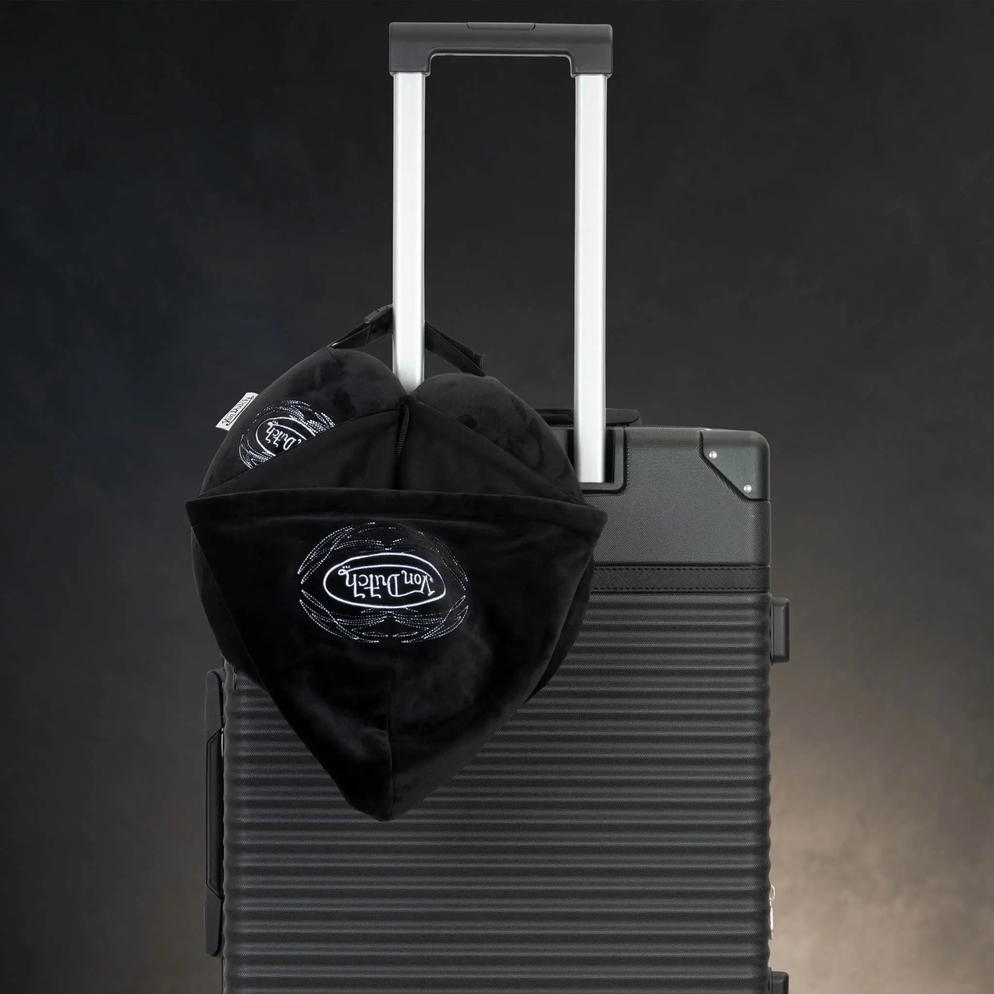 Black bag with a logo on top of a black suitcase against a dark background