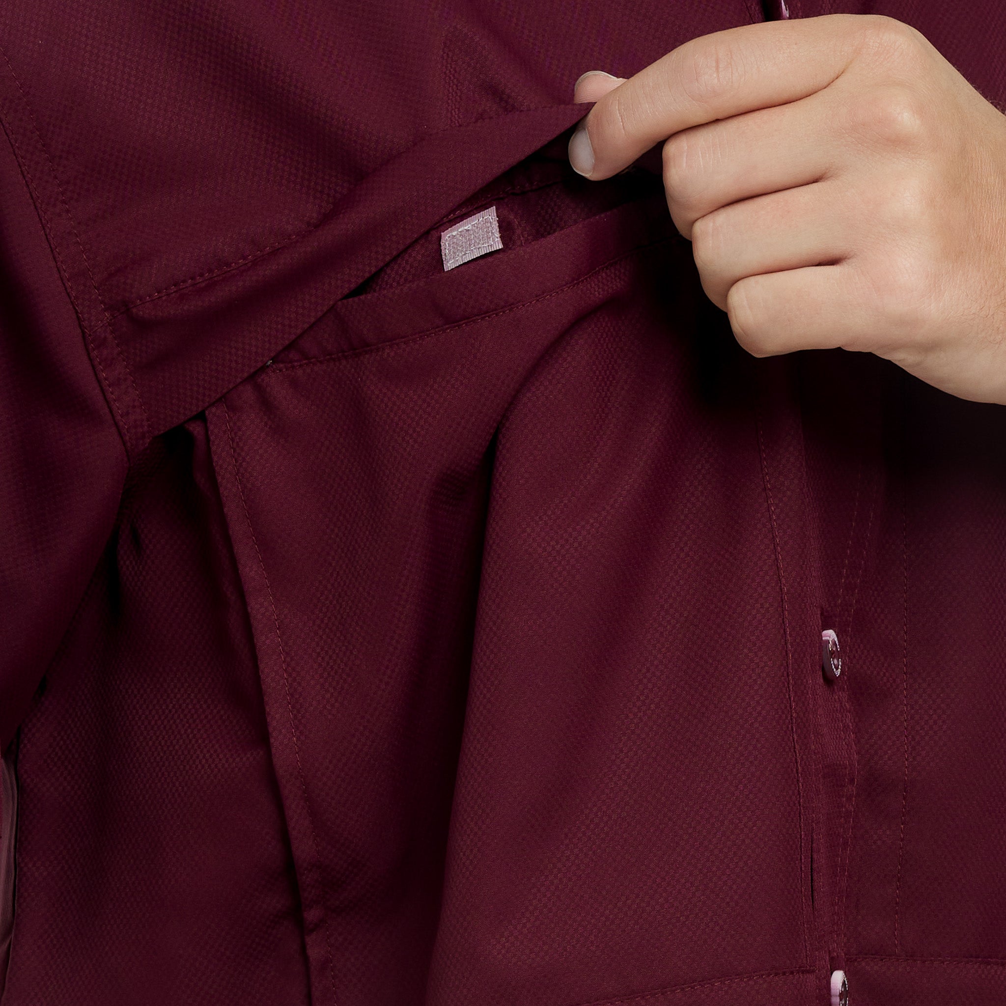 Close-up of a maroon jacket with a hand adjusting the collar.