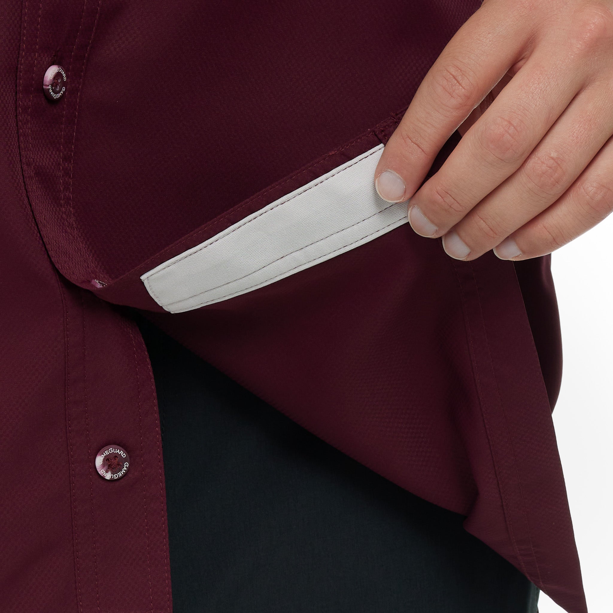 Hand holding a white card against a maroon shirt on a white background