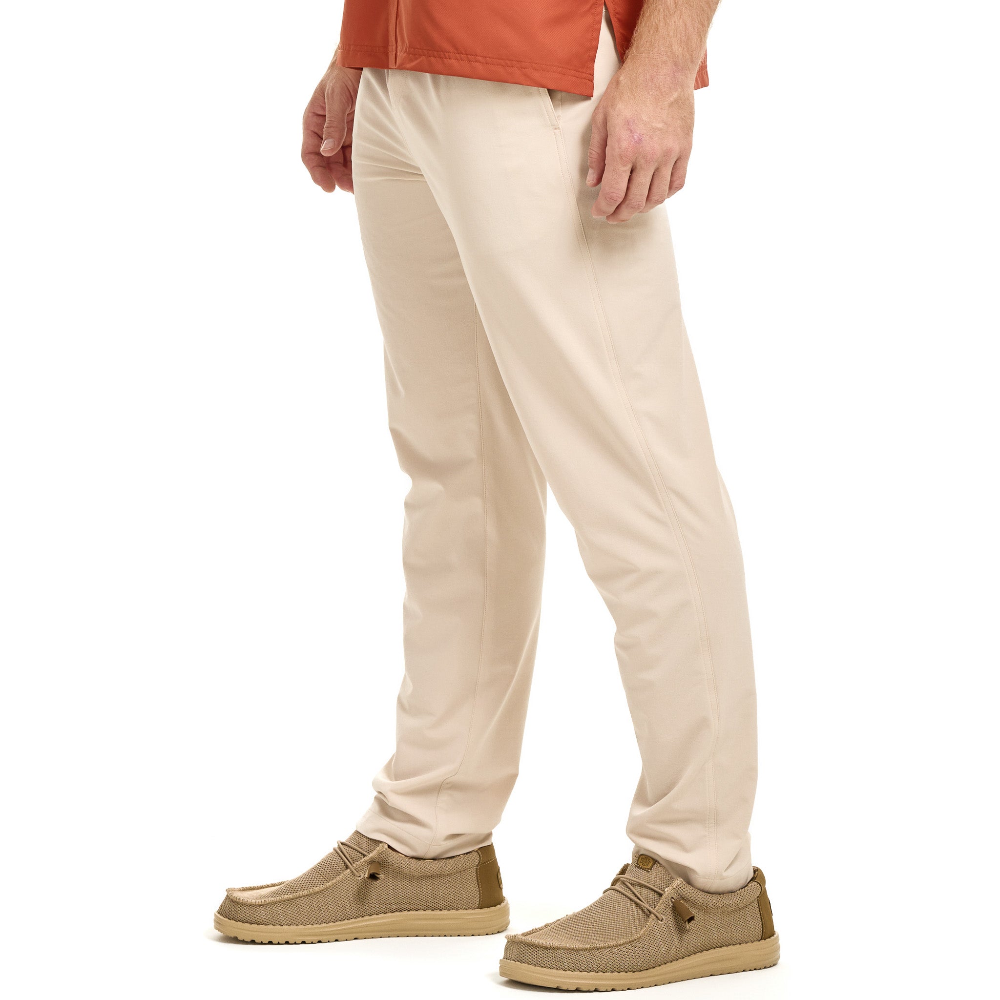 Person wearing beige pants and brown shoes on a white background
