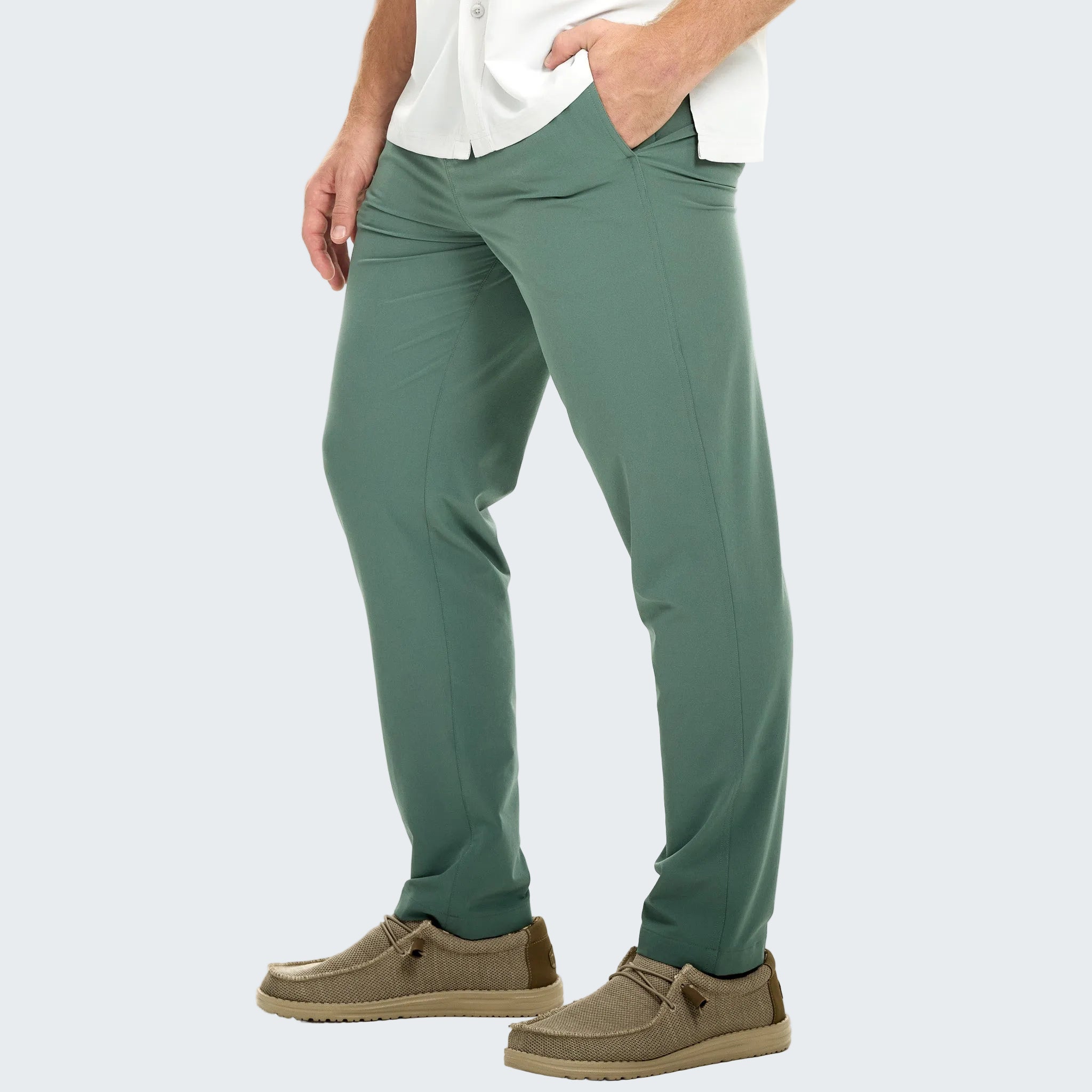 Person wearing green pants and brown shoes on a white background