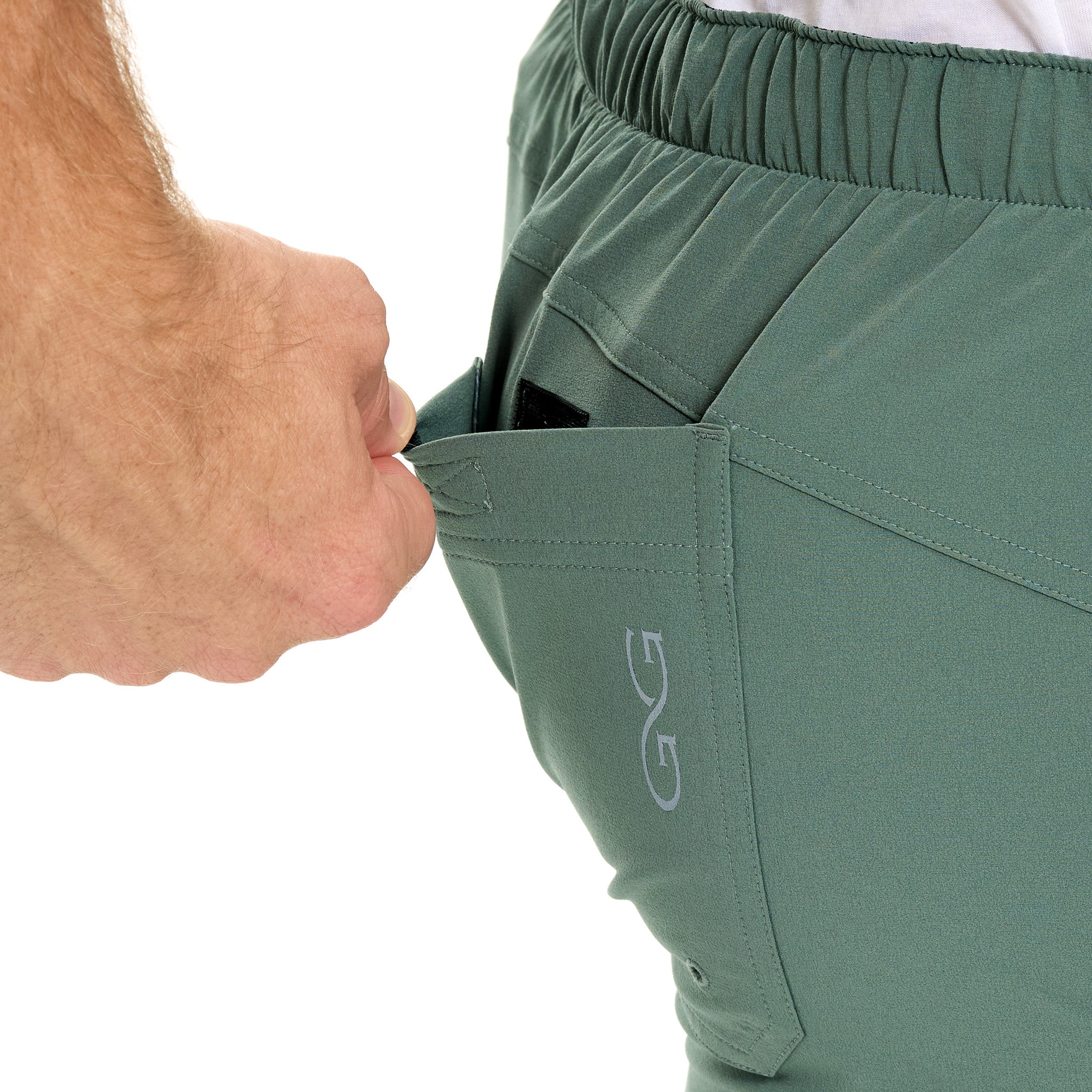 Green shorts with a brand logo being adjusted by a hand on a white background