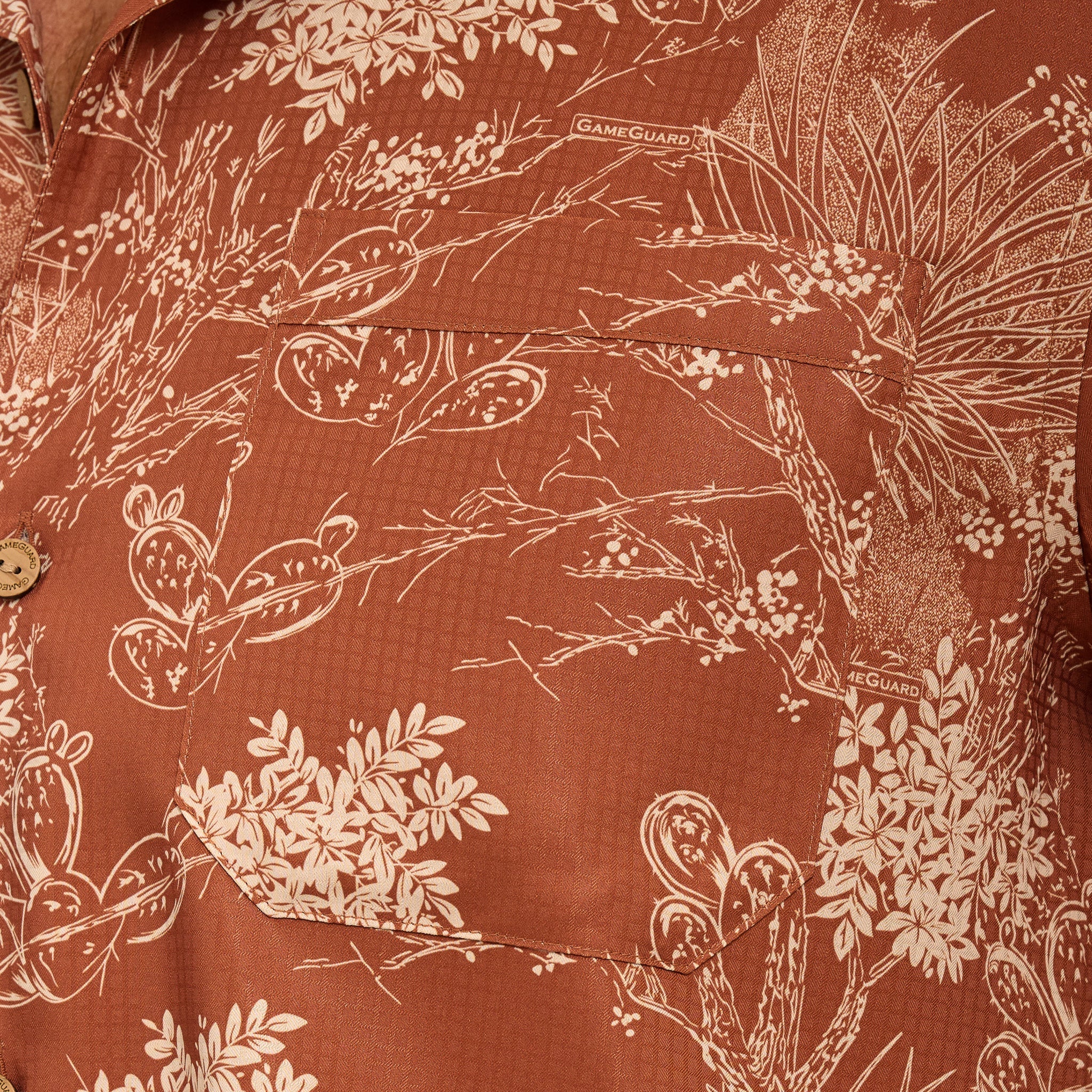 Close-up of a brown shirt with white floral and nature pattern