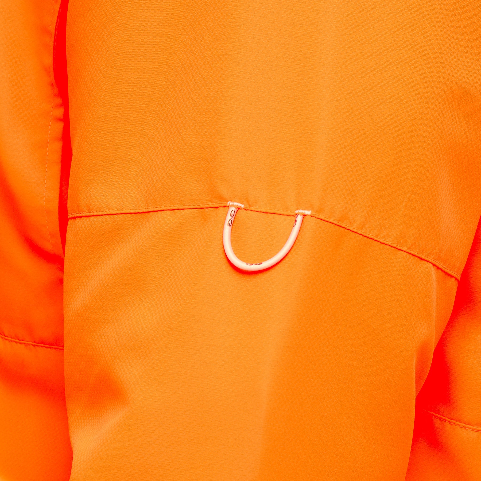 Close-up of a bright orange garment with a small white U-shaped ring detail near the chest pocket.