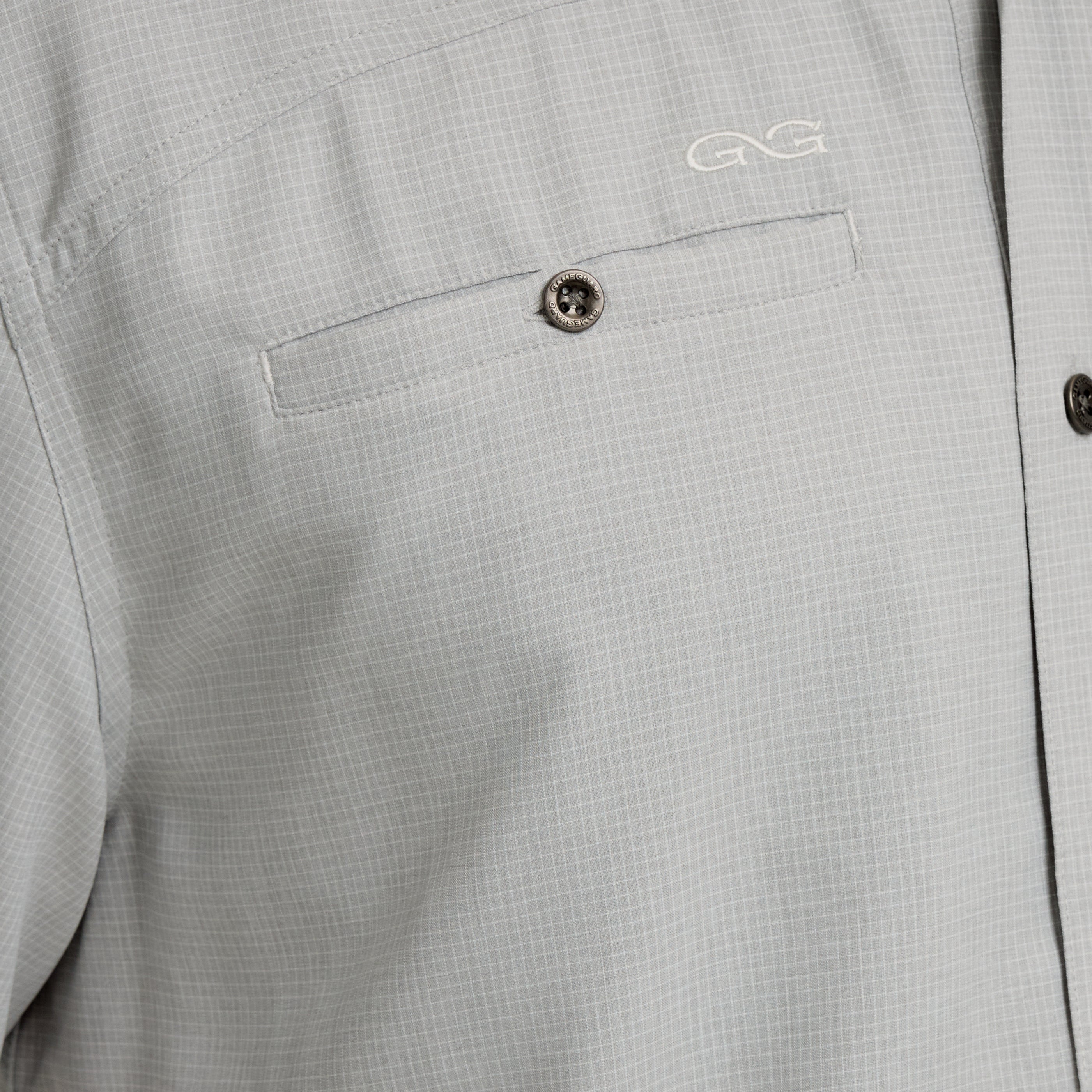 Close-up of a gray shirt with a button and logo on a pocket