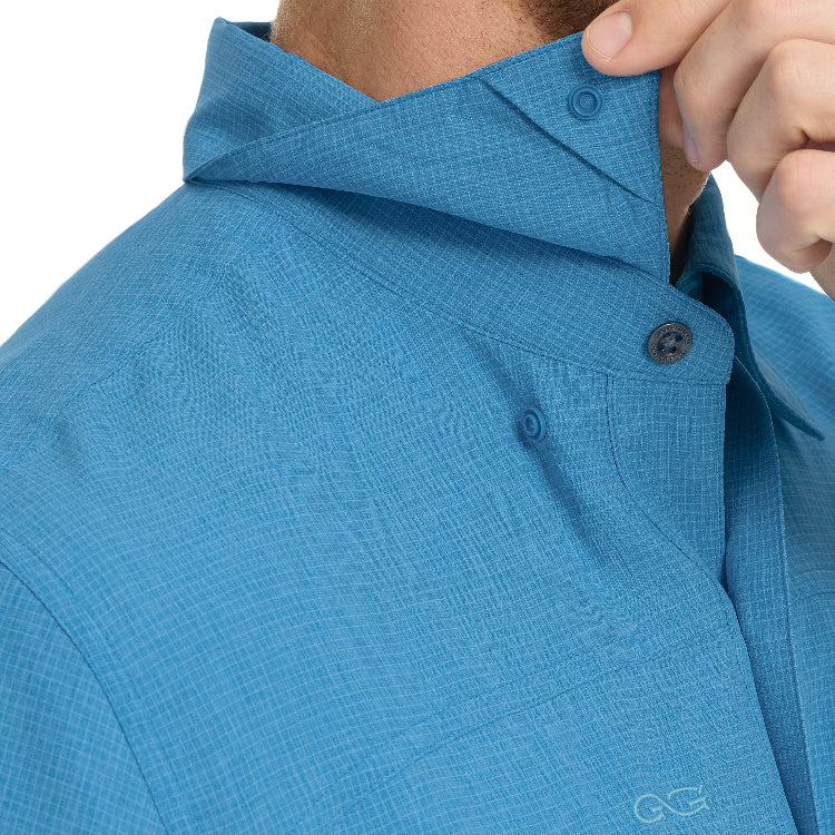 Close-up of a person wearing a blue textured shirt with a brand logo on a white background