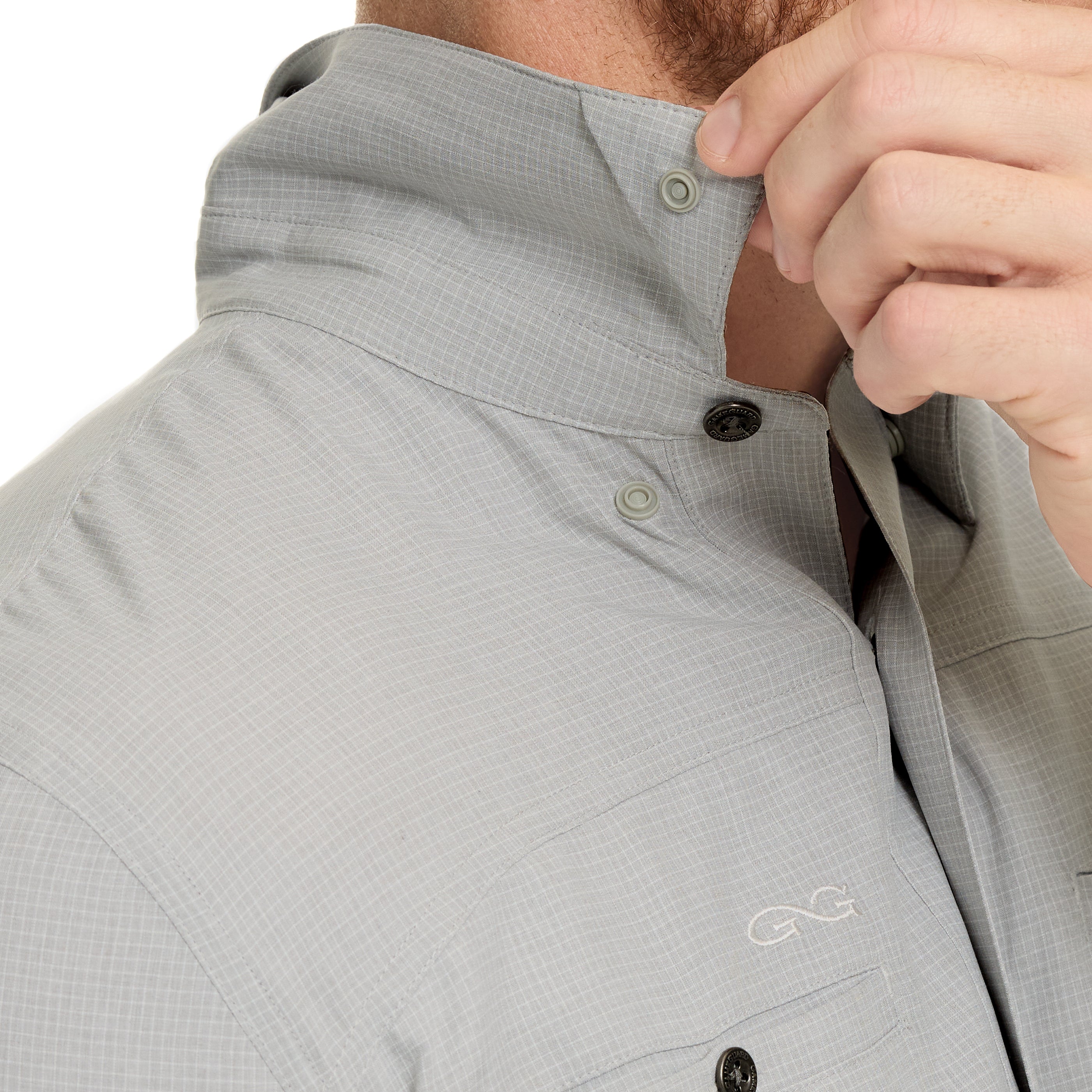 Close-up of a person wearing a gray shirt with a brand logo on the chest.
