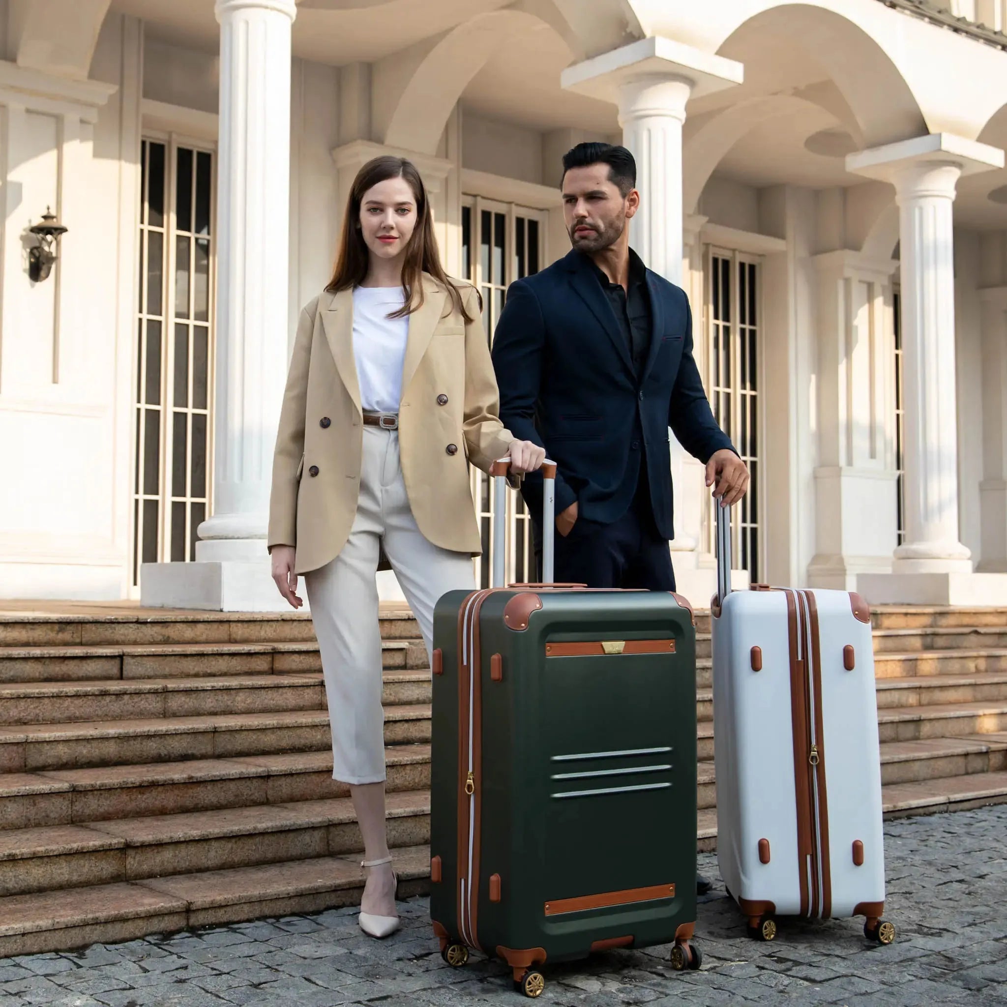 Man and woman with green and white suitcases in front of a classical building.