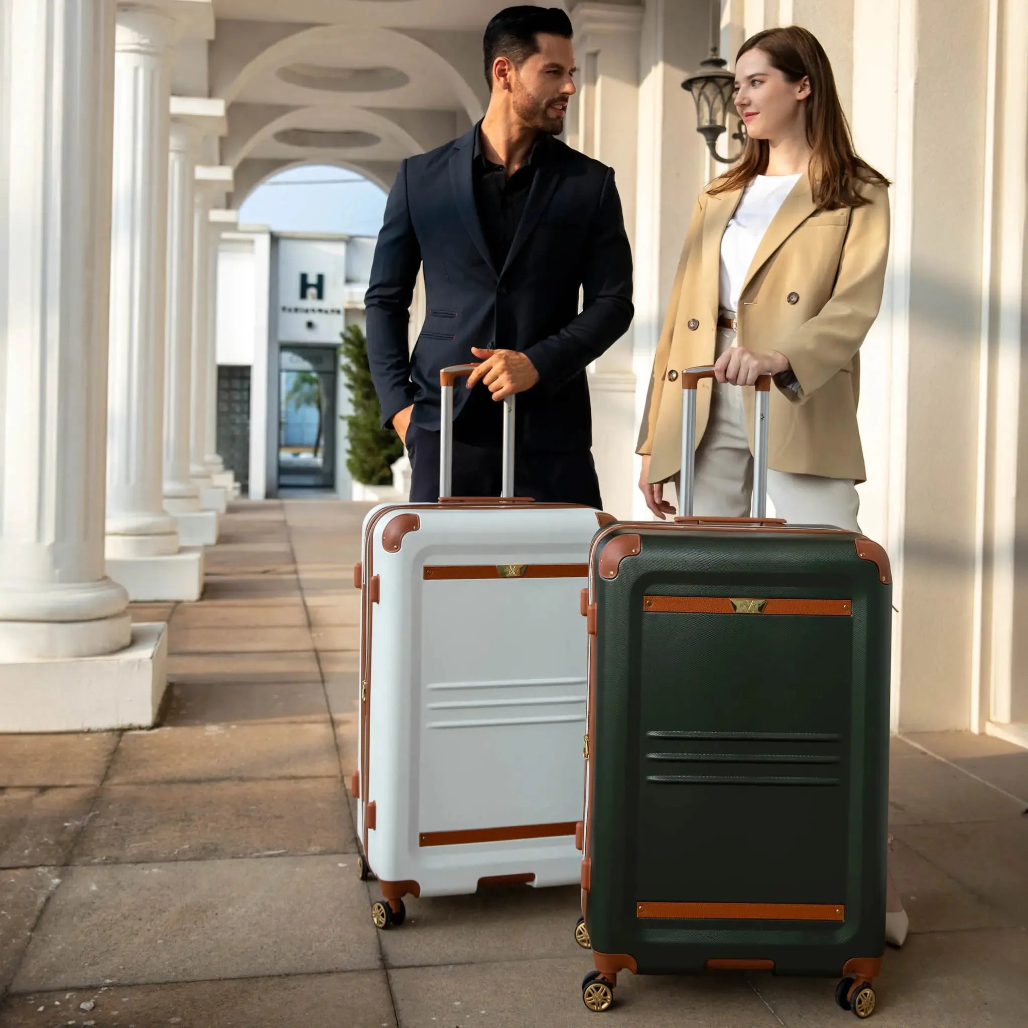 Man and woman walking with suitcases in front of a hotel entrance