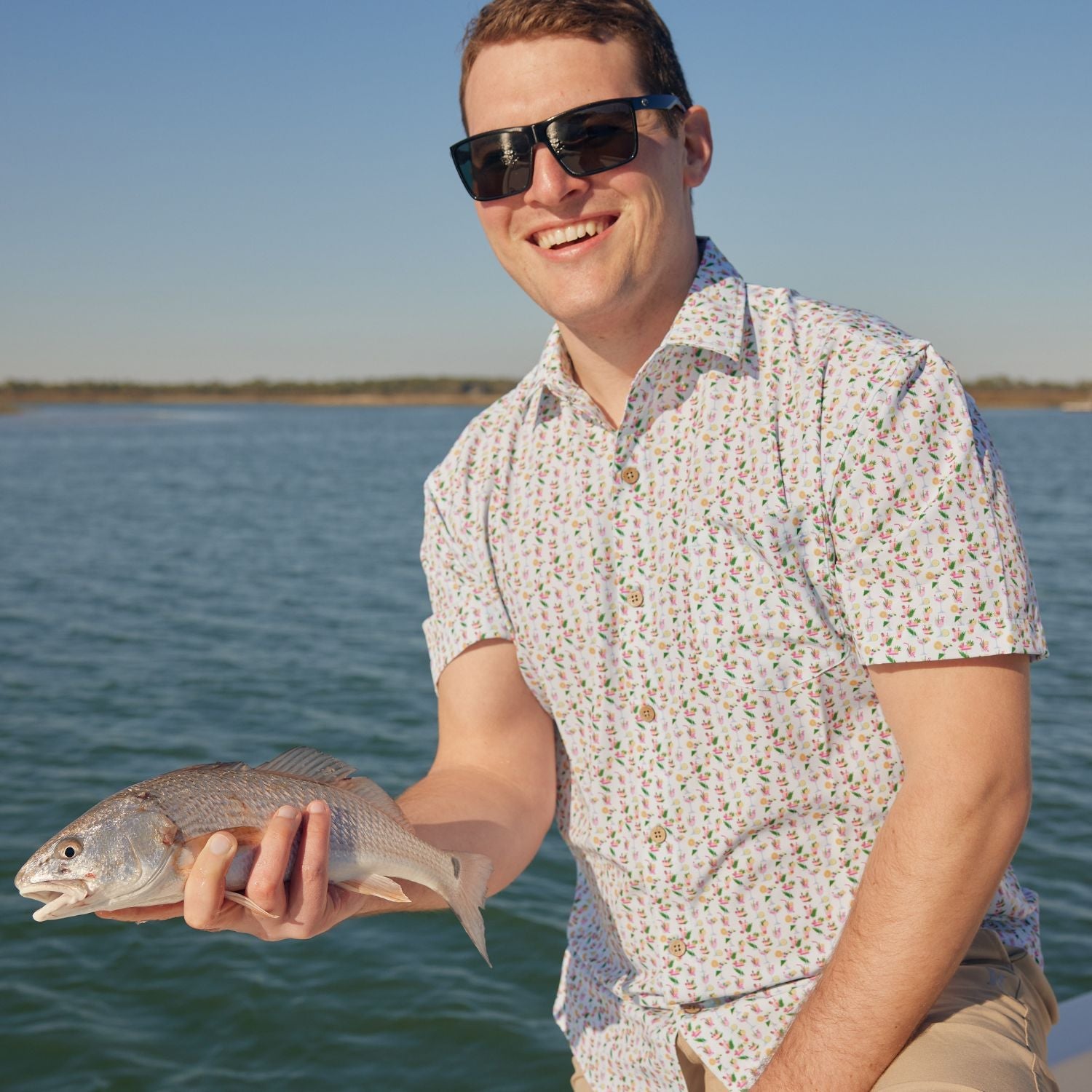 Man holding a fish by a body of water