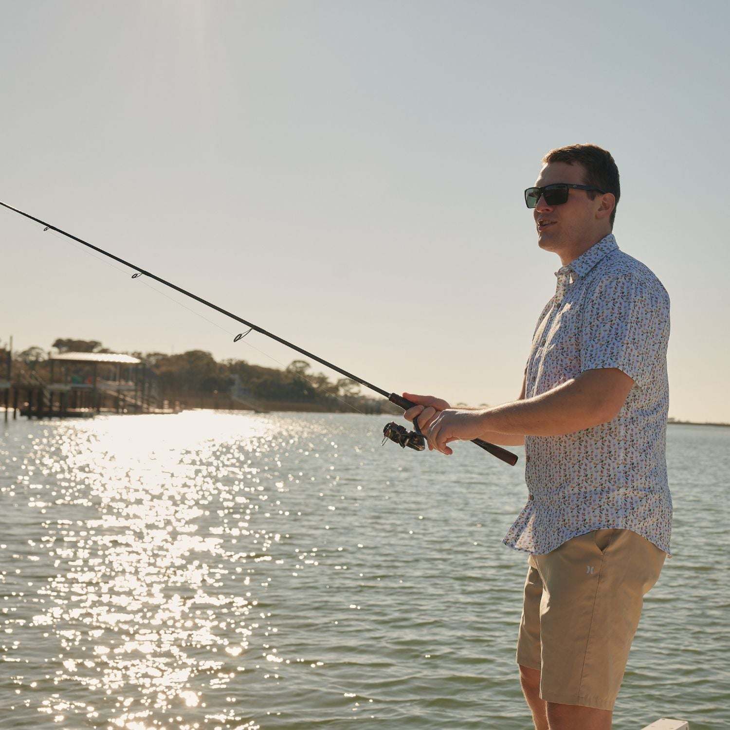 Man fishing by a body of water with a clear sky