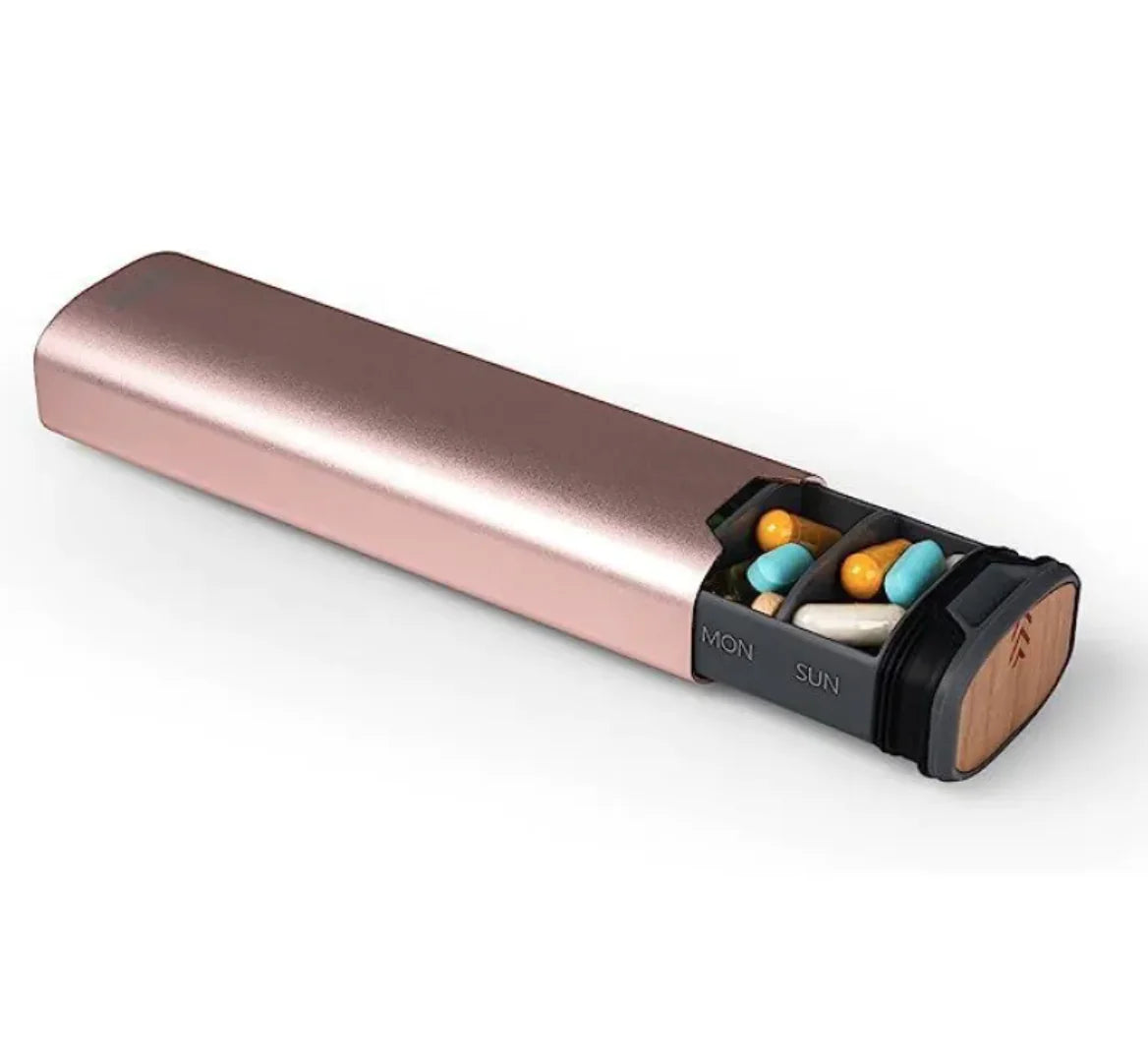 Rose gold pill organizer with colorful pills on a white background