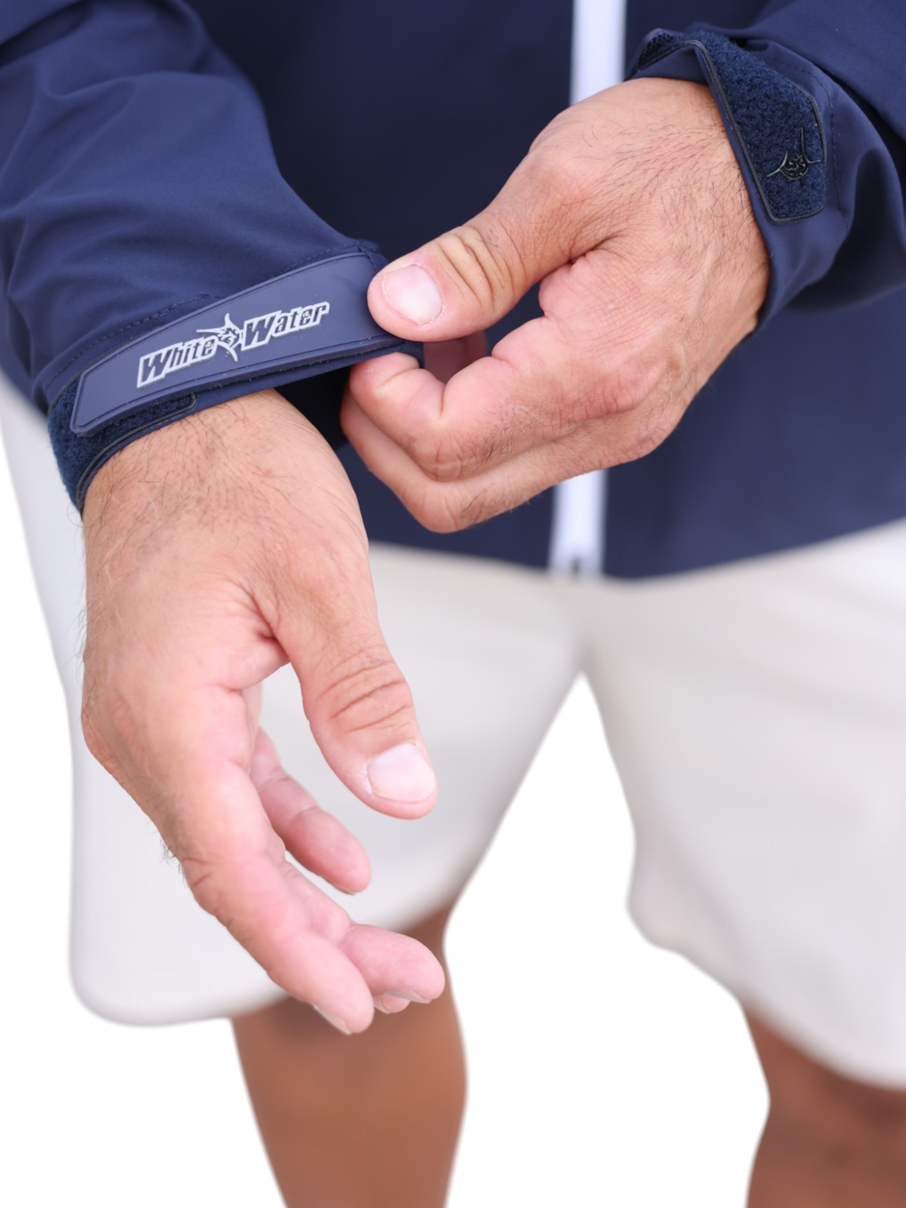 Person wearing a navy jacket with a visible brand logo, adjusting the sleeve.