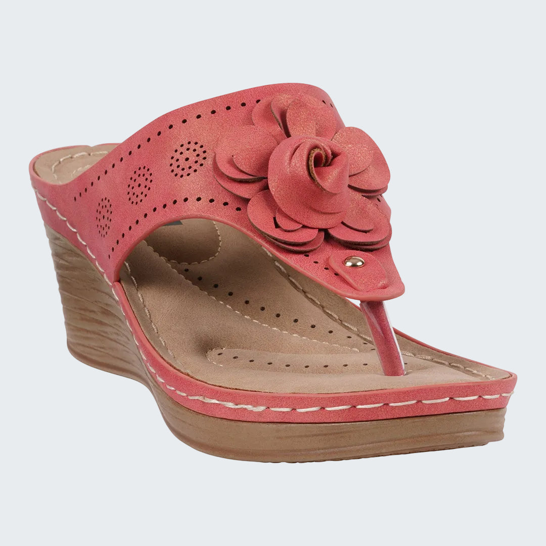 Pink wedge sandal with a floral design on a white background