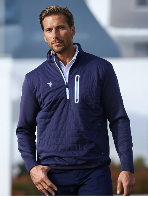 Man wearing a navy blue jacket with a logo, standing outdoors.
