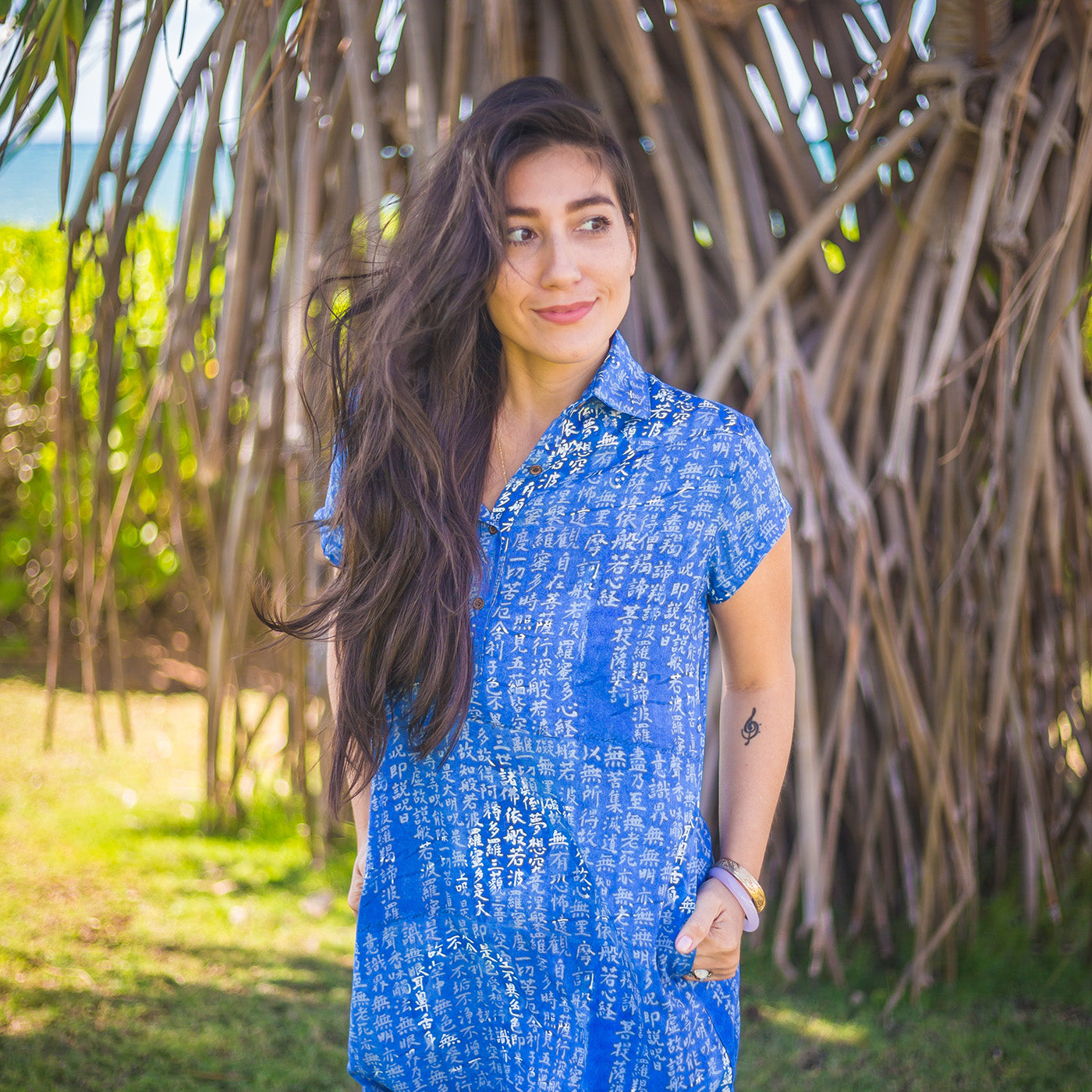 Woman in a blue dress standing in front of a natural, leafy background