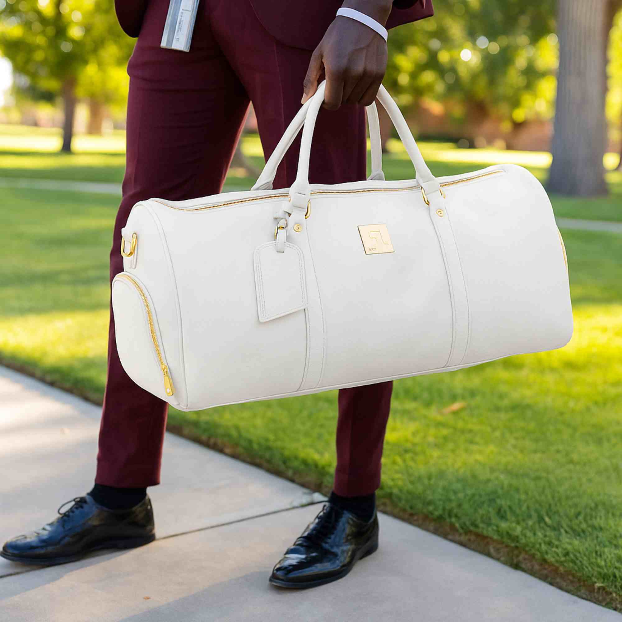 Person holding a white duffel bag outdoors on a sunny day