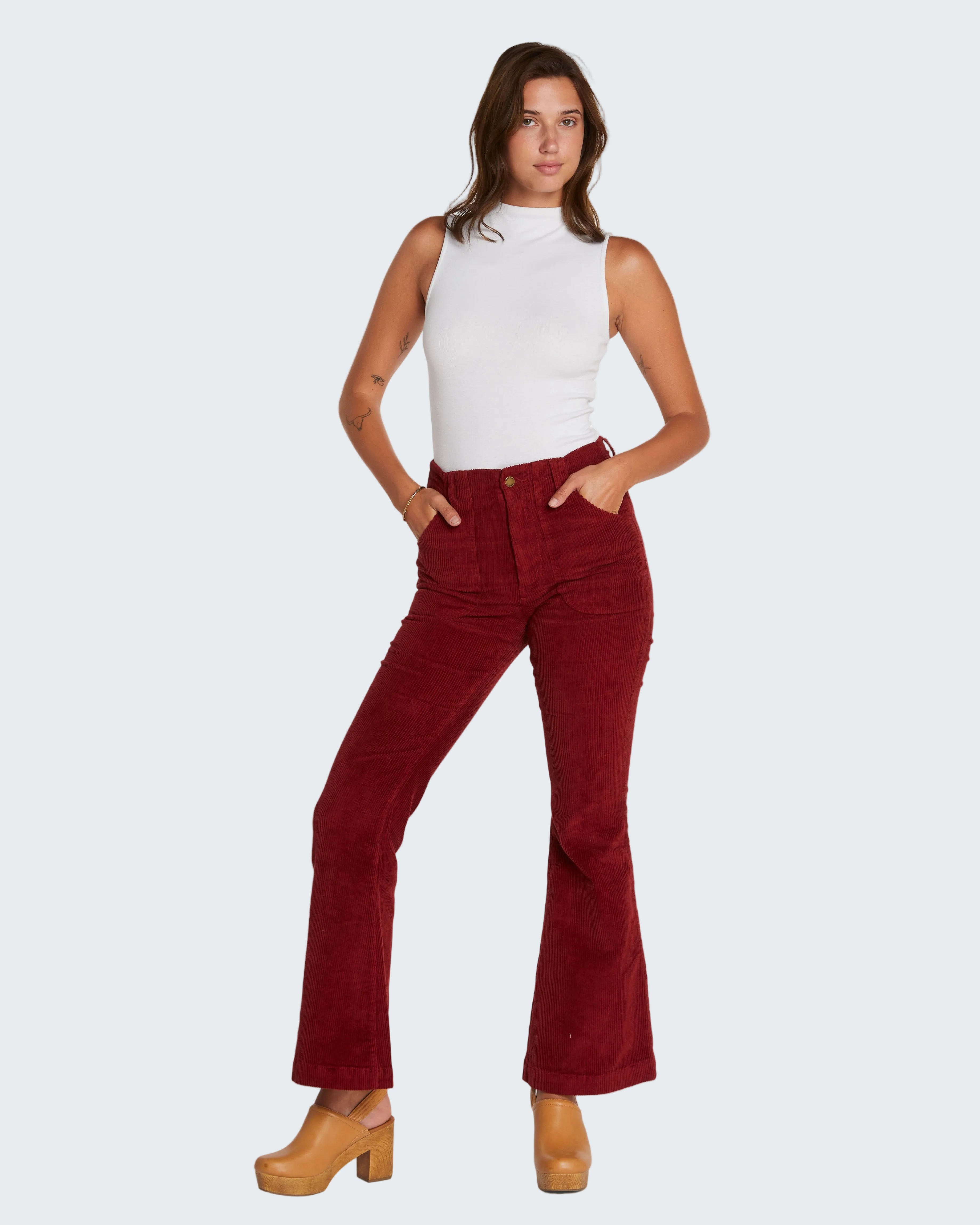 Woman wearing red flared jeans and a white top on a white background