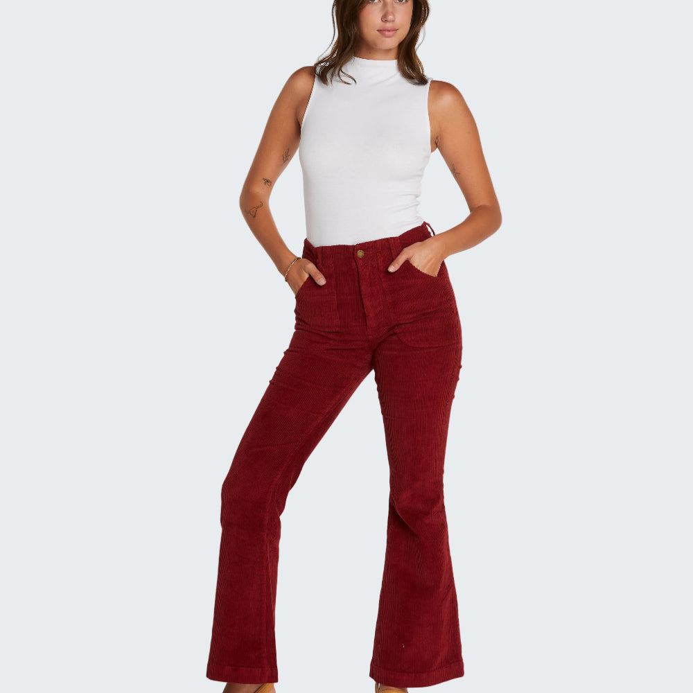 Woman wearing red flared jeans and a white top on a white background