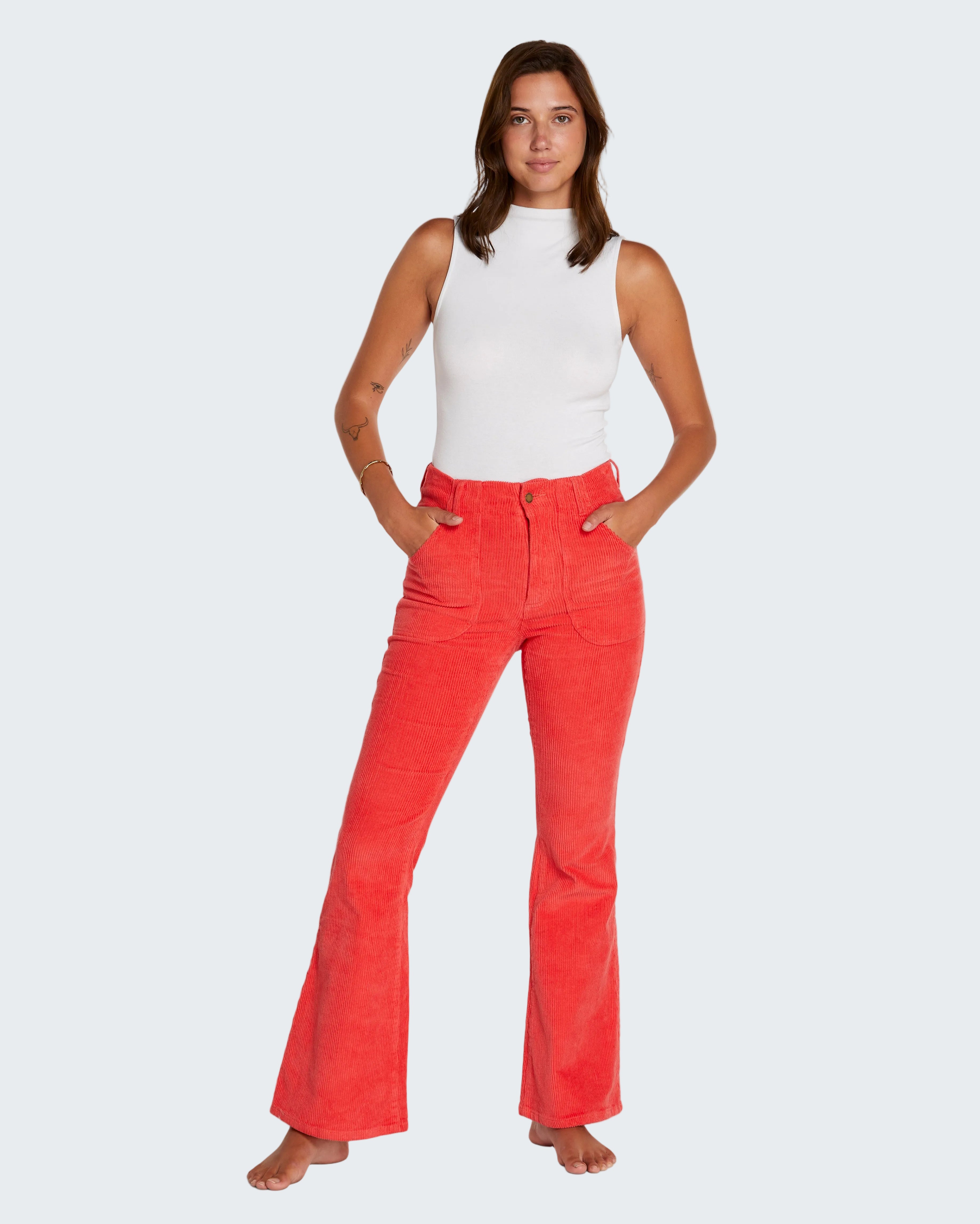 Woman wearing red flared pants and a white top on a white background