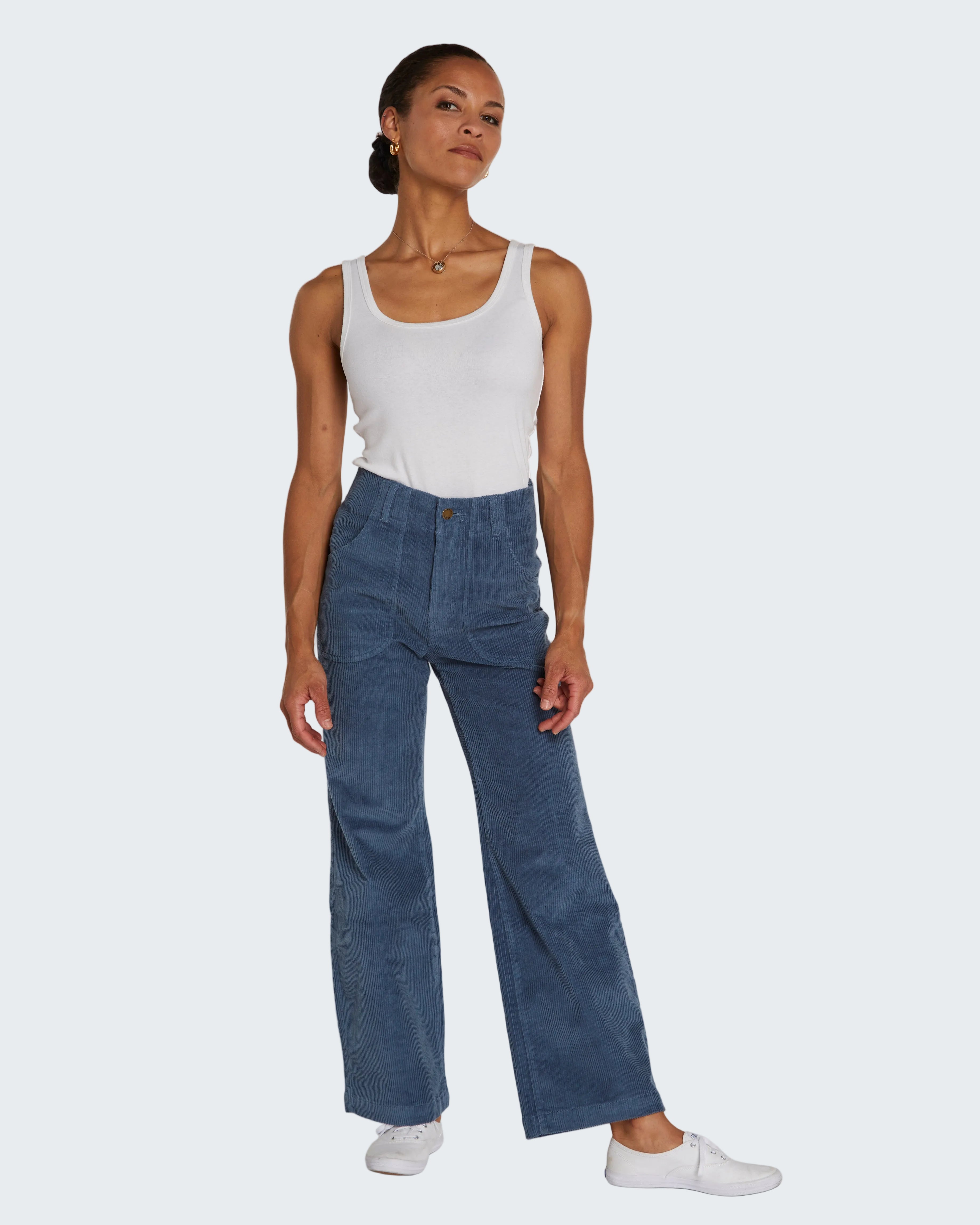 Woman wearing a white tank top and blue pants on a white background
