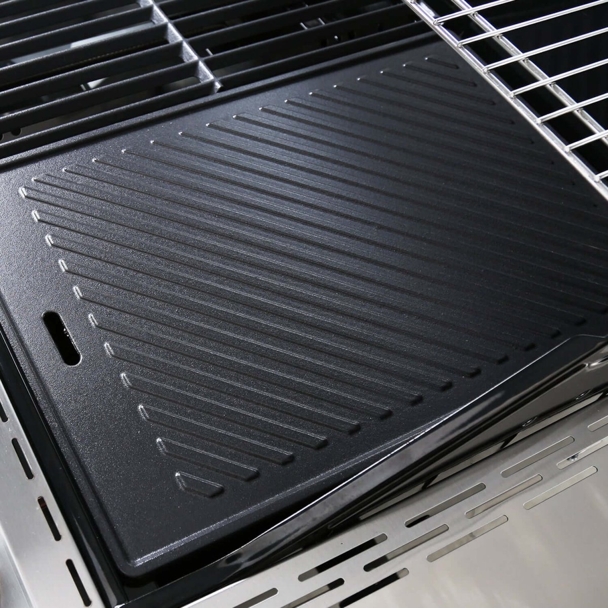 Black grill pan with ribbed surface on a grill