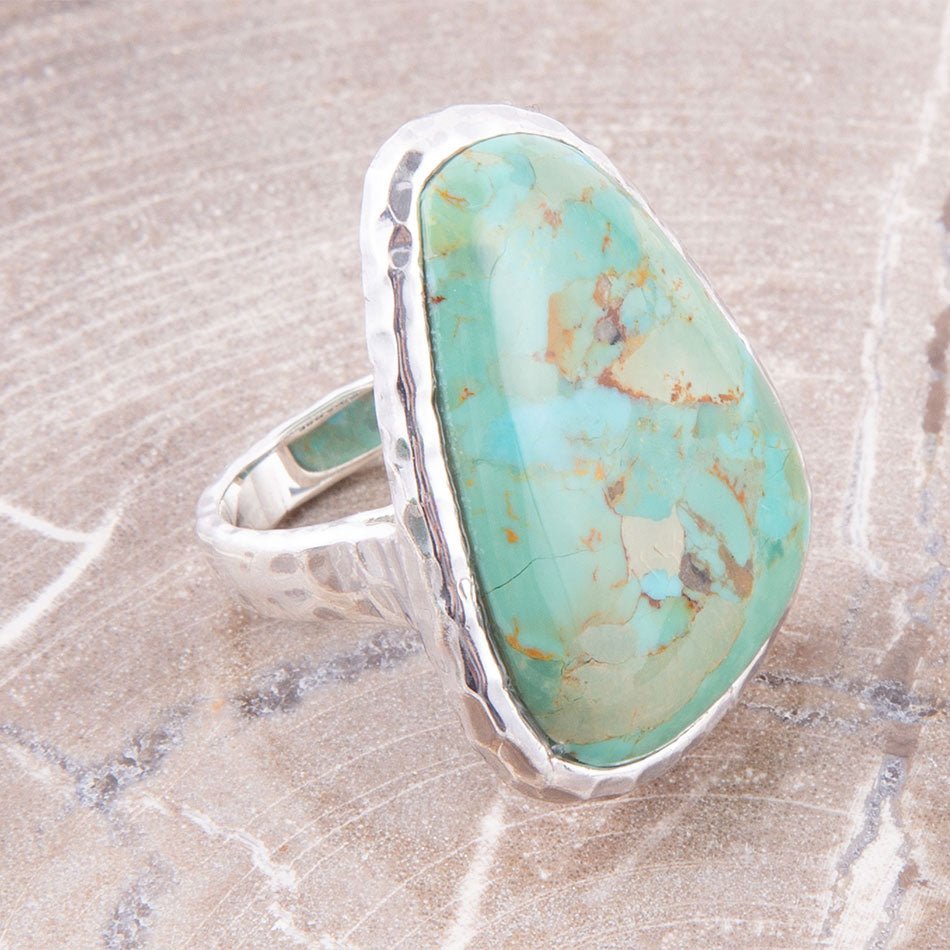 Turquoise ring with silver band on a marble surface