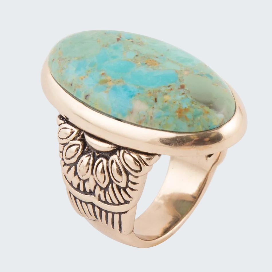 Ring with turquoise stone and gold band on a white background