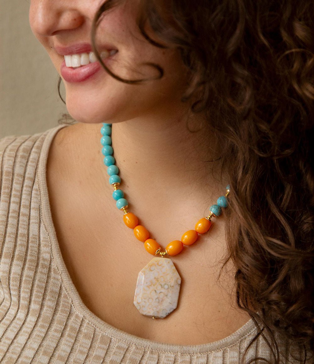 Woman wearing a colorful beaded necklace with a large pendant.