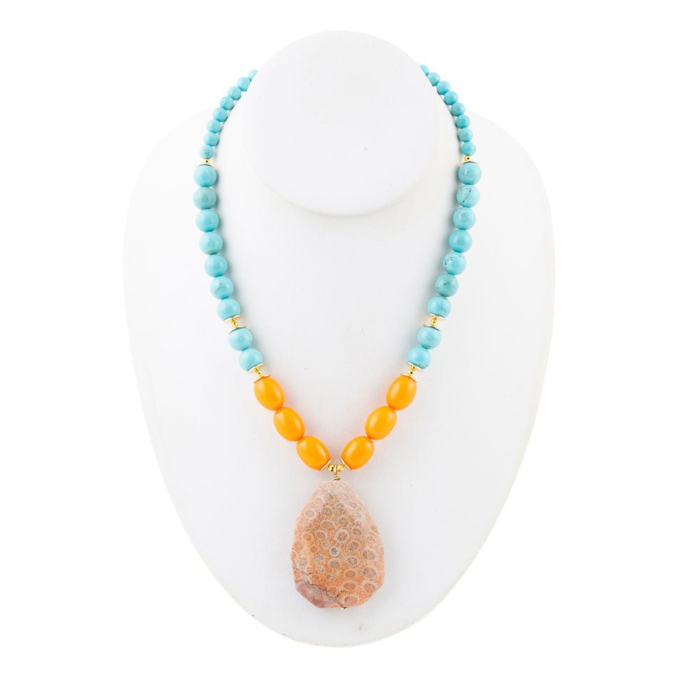 Necklace with turquoise and orange beads on a white stand
