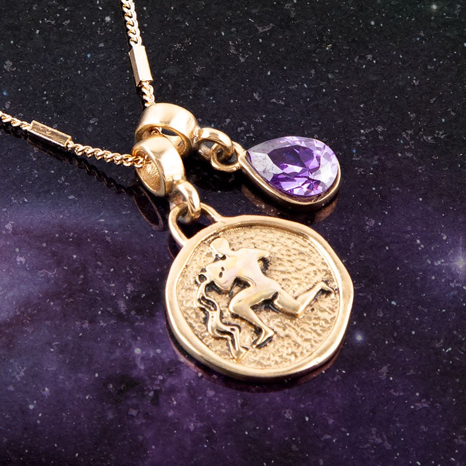 Gold necklace with a zodiac pendant and purple gemstone on a dark background