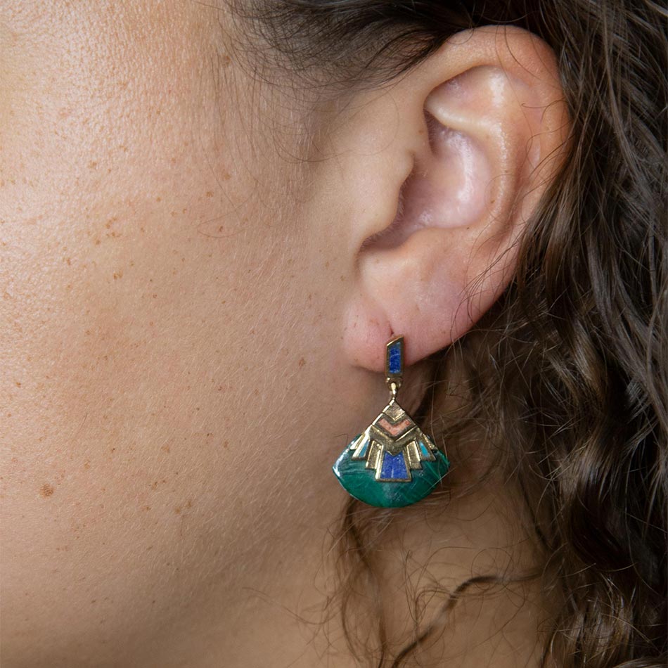 Close-up of an ear wearing a green and gold earring.