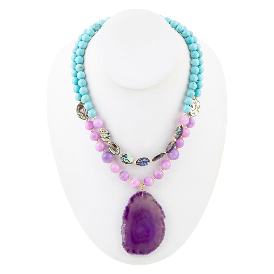 Necklace with turquoise and purple beads on a white stand