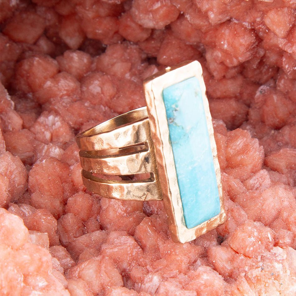 Gold ring with turquoise stone on a pink stone background