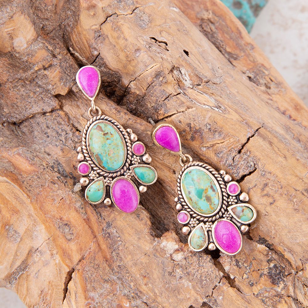 Pair of earrings with pink and green stones on a wooden surface